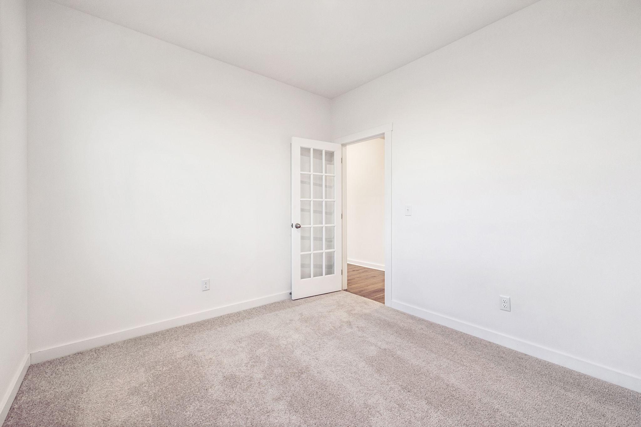 Empty bedroom with French doors, beige carpet, and white walls in Davidson Homes The Willow, Calista Farms, White House, TN