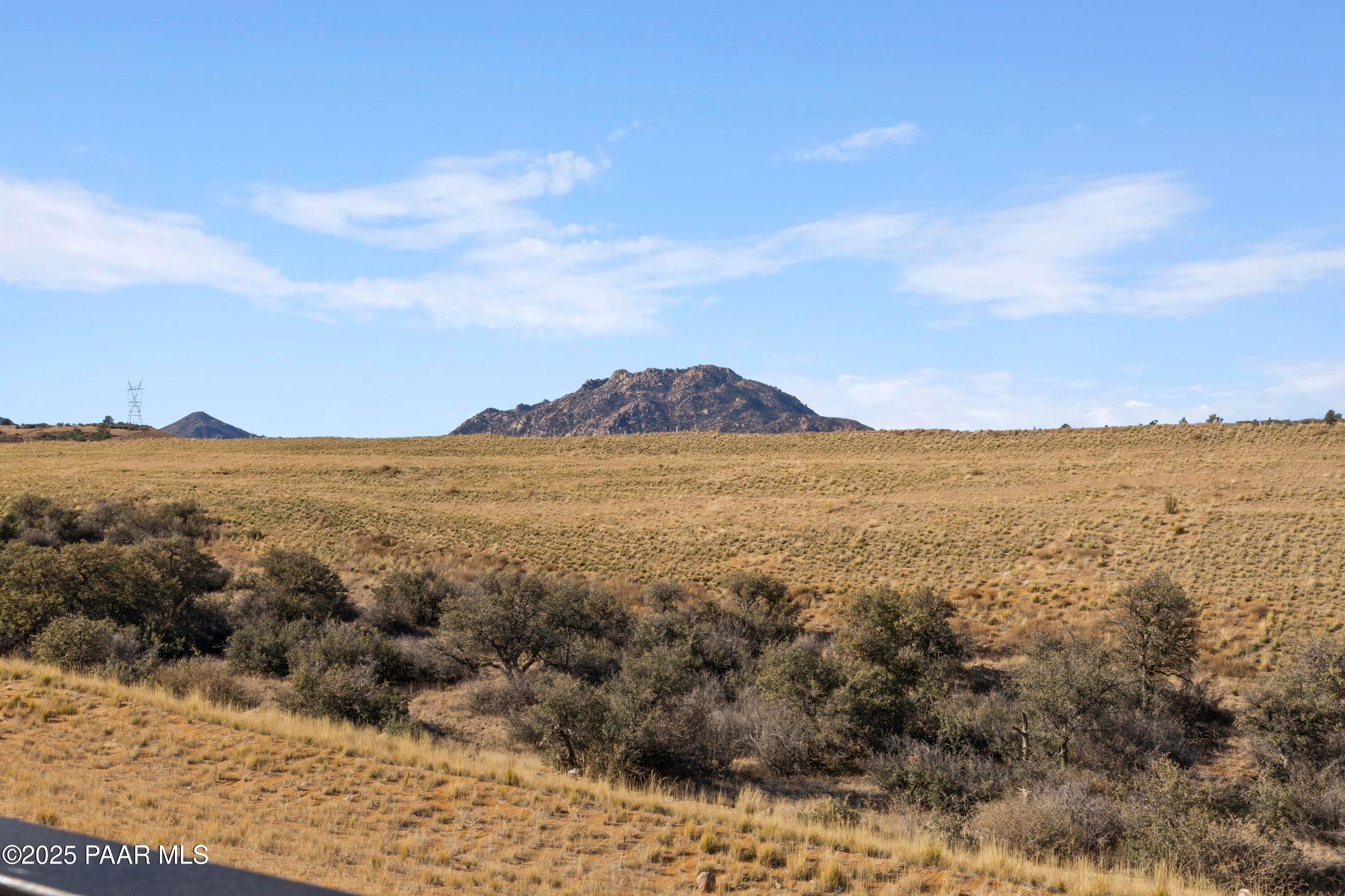 Rugged granite mountain peak overlooking golden grasslands and desert shrubs in Hidden Hills, Prescott, Arizona