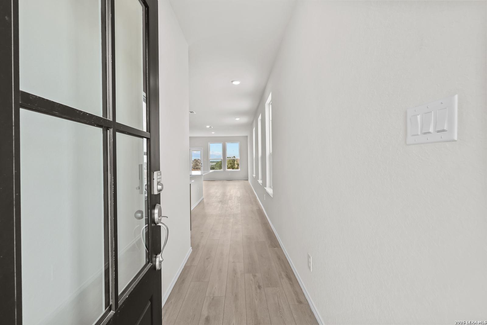 Bright entryway with wood-style flooring and modern glass door in The Gillian B floor plan at Meadows at Oak Creek.