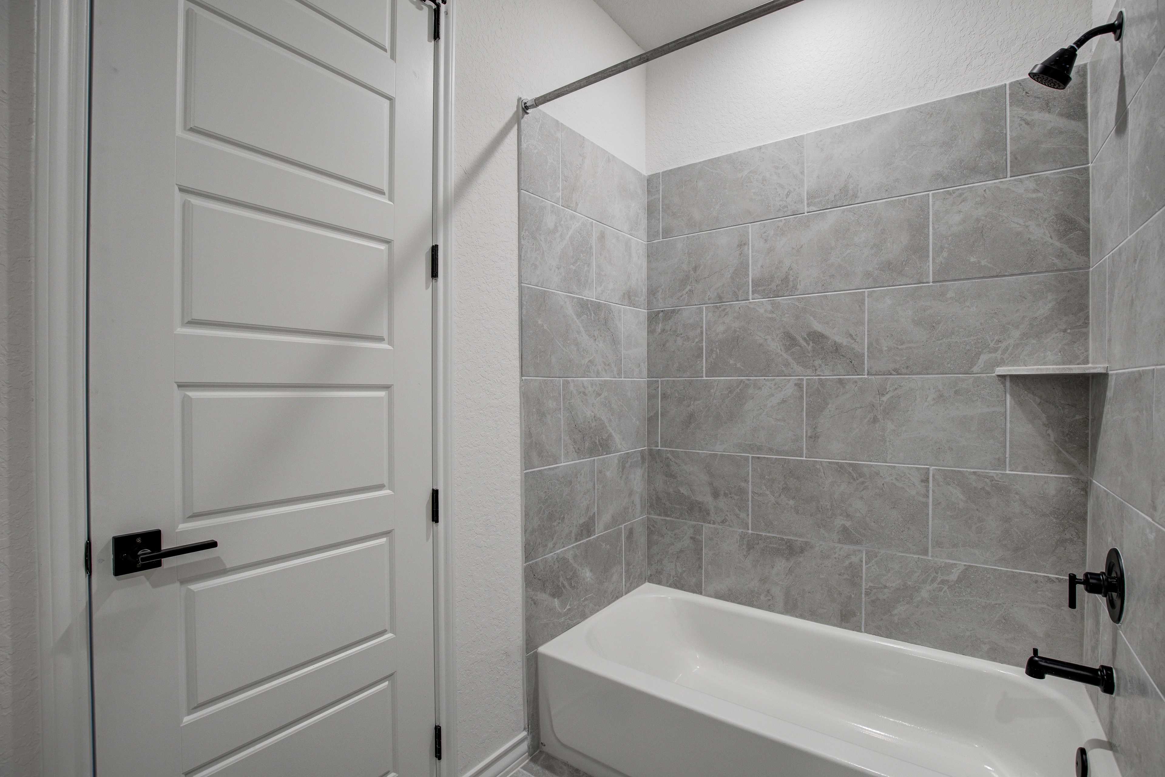 Spacious master bathroom in The Lanier with freestanding tub, gray tiled walk-in shower, and paneled double doors