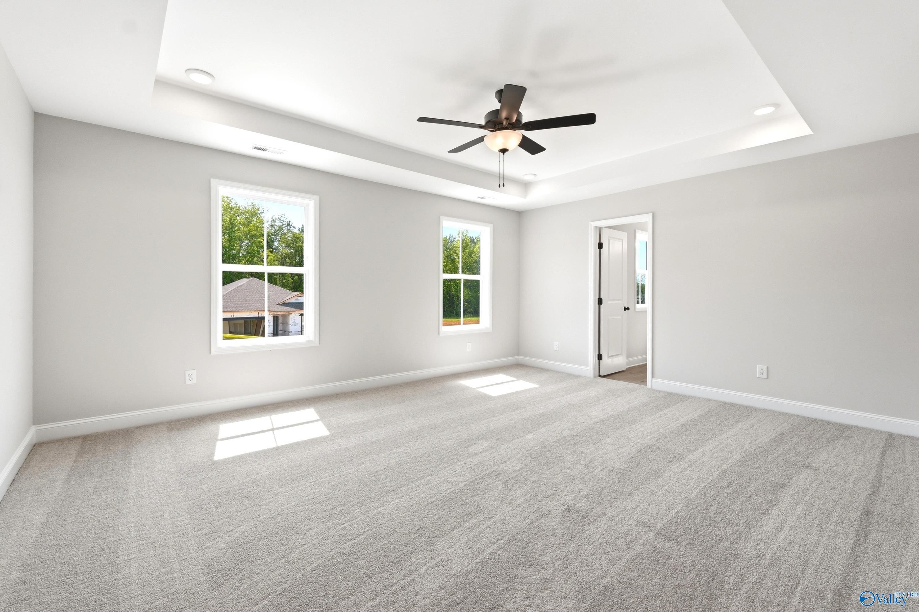 Spacious bedroom with tray ceiling and ceiling fan in The Russell A floor plan by Davidson Homes in Huntsville, Alabama.