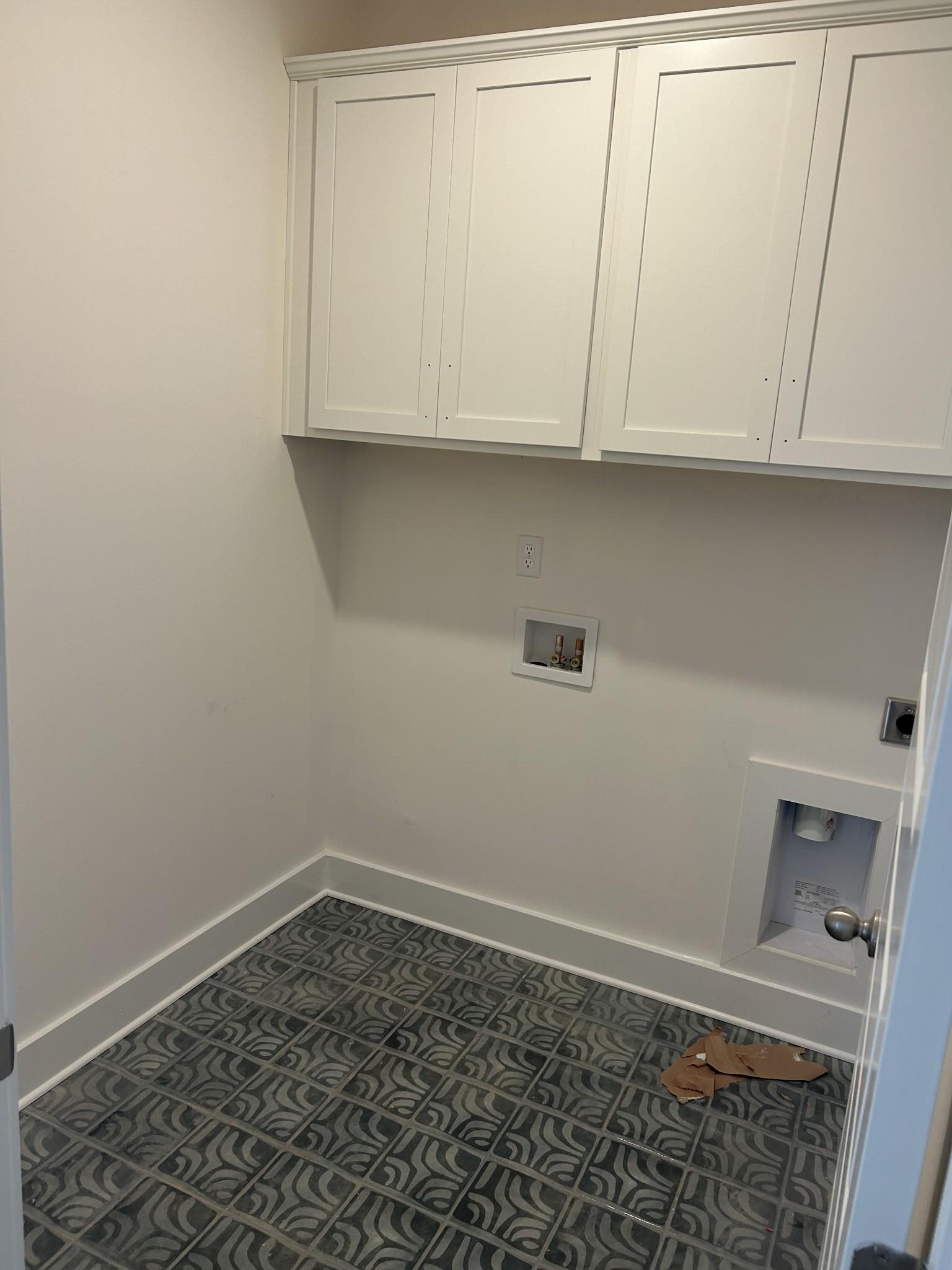 Modern laundry room with white shaker cabinets, utility sink, and blue mosaic tile floor in Davidson Homes Ridgeport D, Mt. Juliet