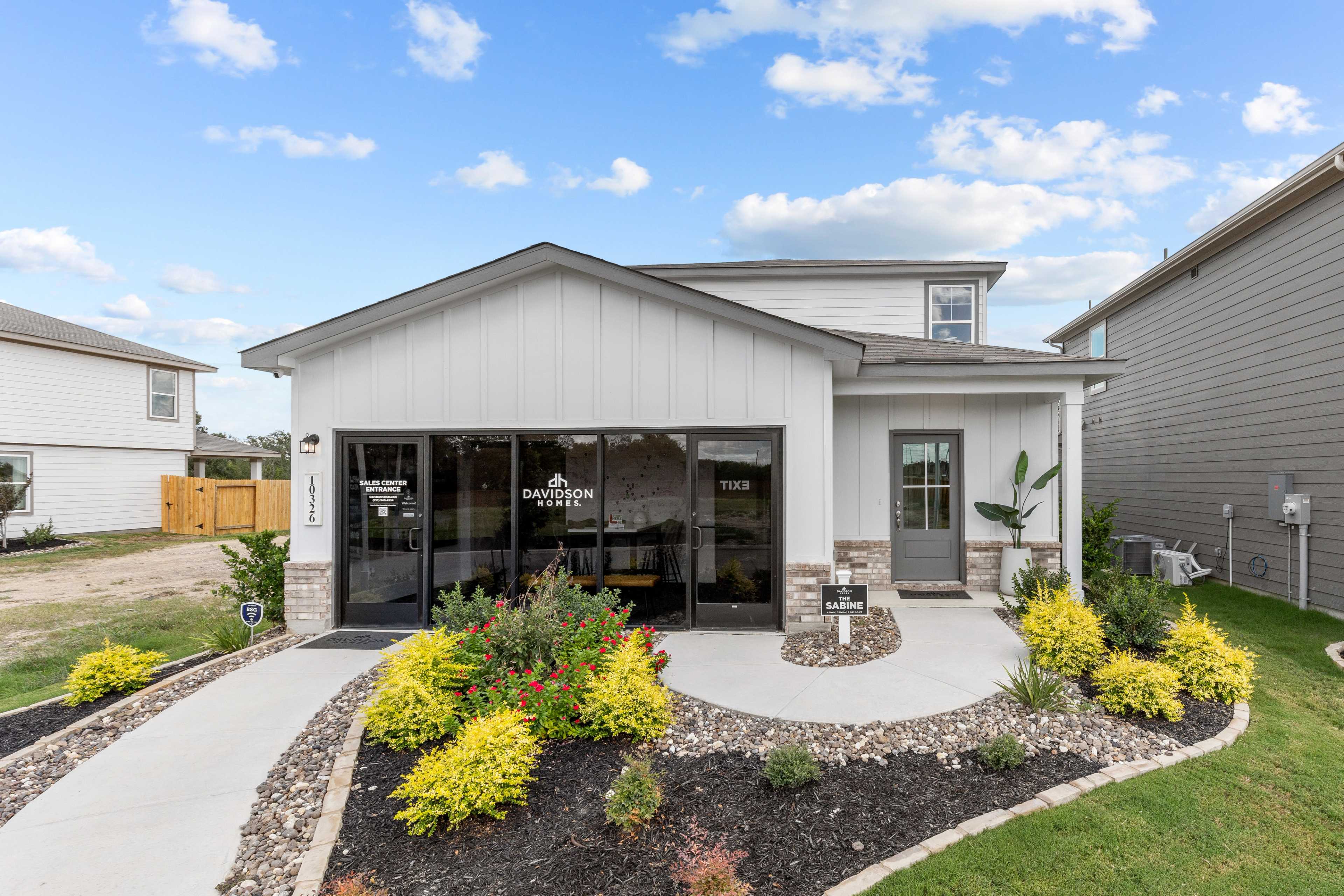 Modern home exterior at Applewhite Meadows in San Antonio TX by Davidson Homes featuring attached garage, covered entry, and vibrant landscaping