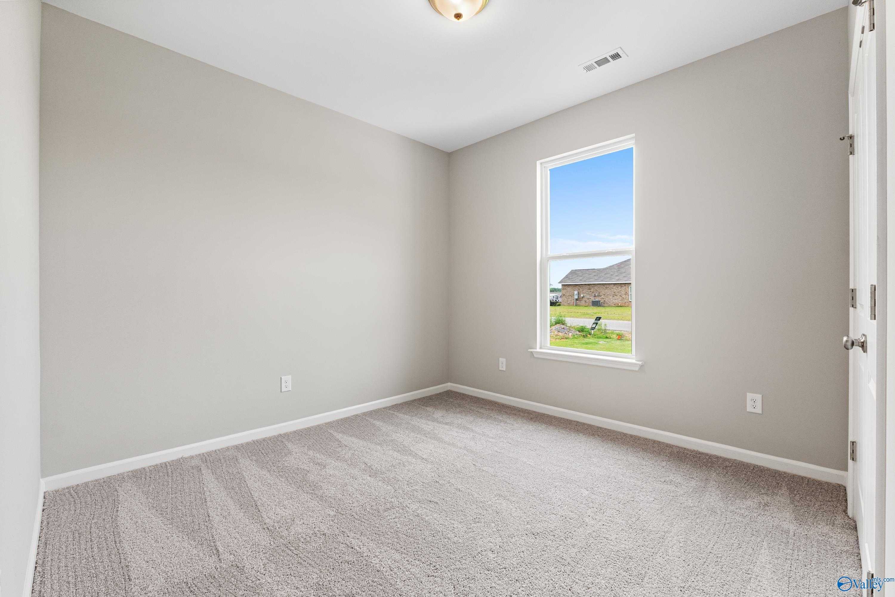 Cozy bedroom with light gray walls, plush carpet, and large window overlooking backyard in Davidson Homes The Aurora, Fayetteville, TN