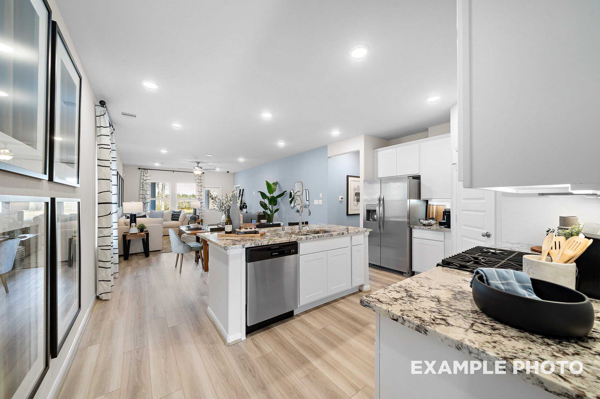 Open-concept kitchen featuring white cabinets, granite countertops, stainless appliances, and adjacent dining area in Davidson Homes San Marcos D, San Antonio
