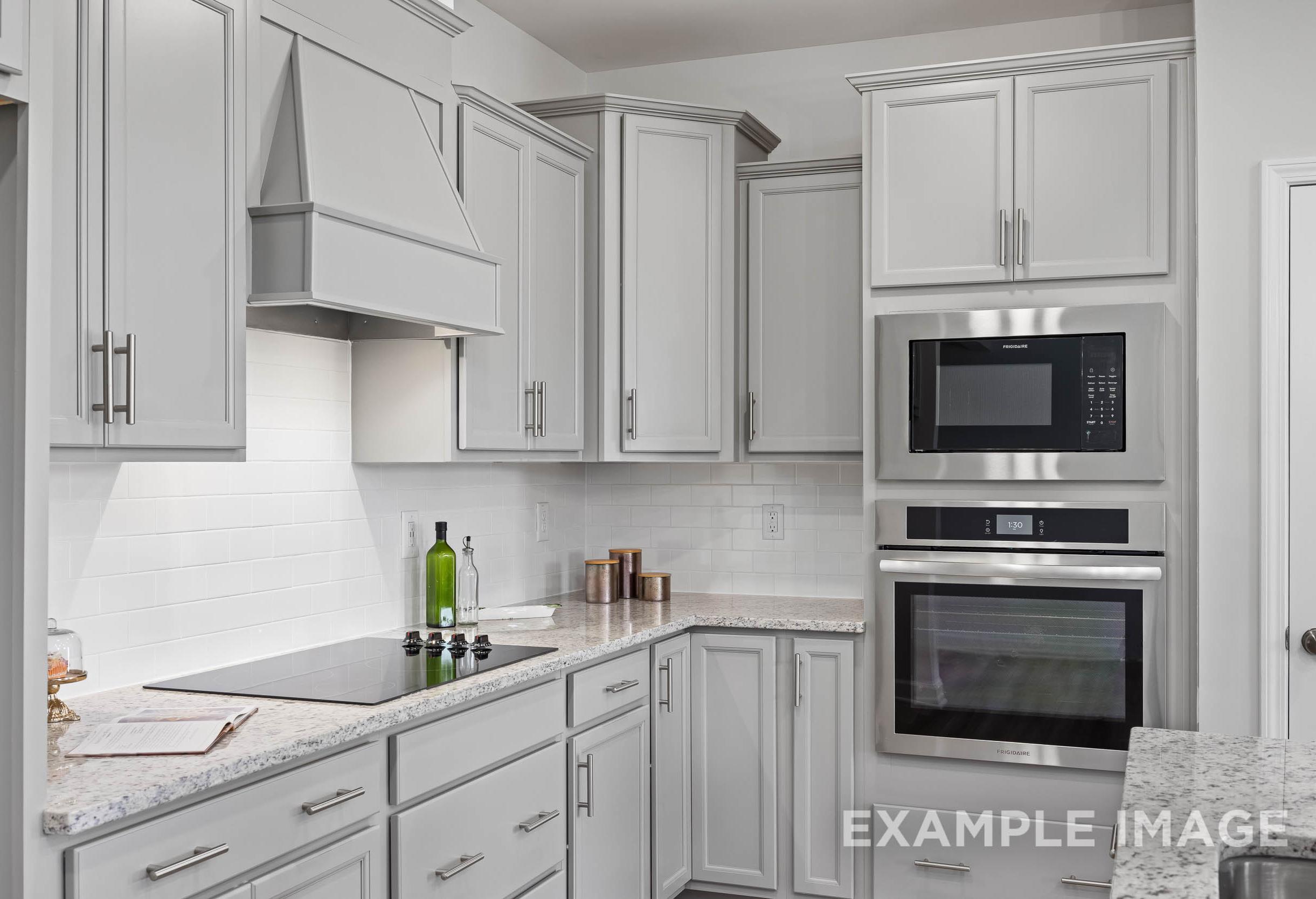 Modern kitchen in The Daphne C by Davidson Homes featuring white shaker cabinets, stainless steel double oven, and quartz counters