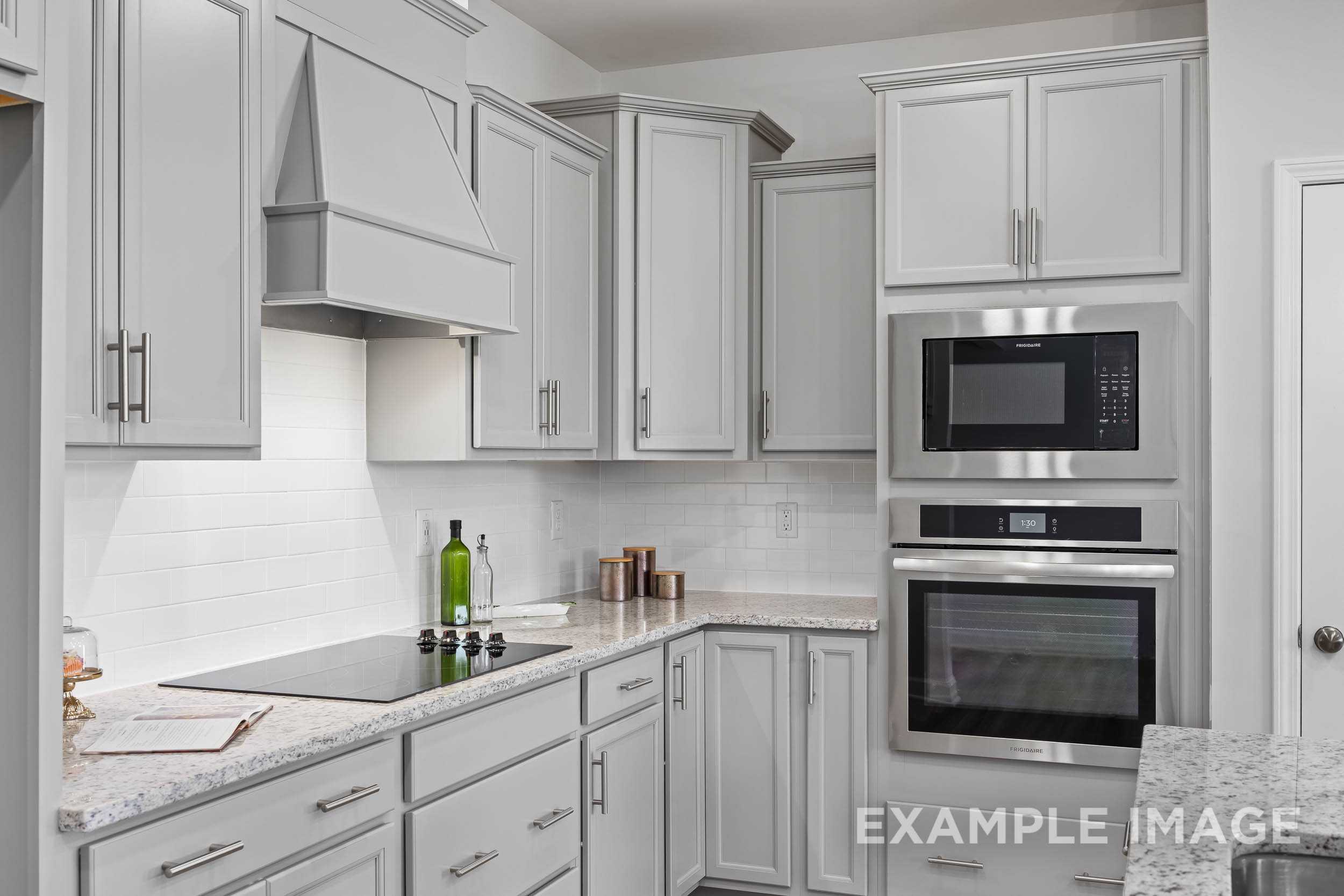 Modern kitchen in The Daphne C by Davidson Homes featuring white shaker cabinets, stainless steel double oven, and quartz counters
