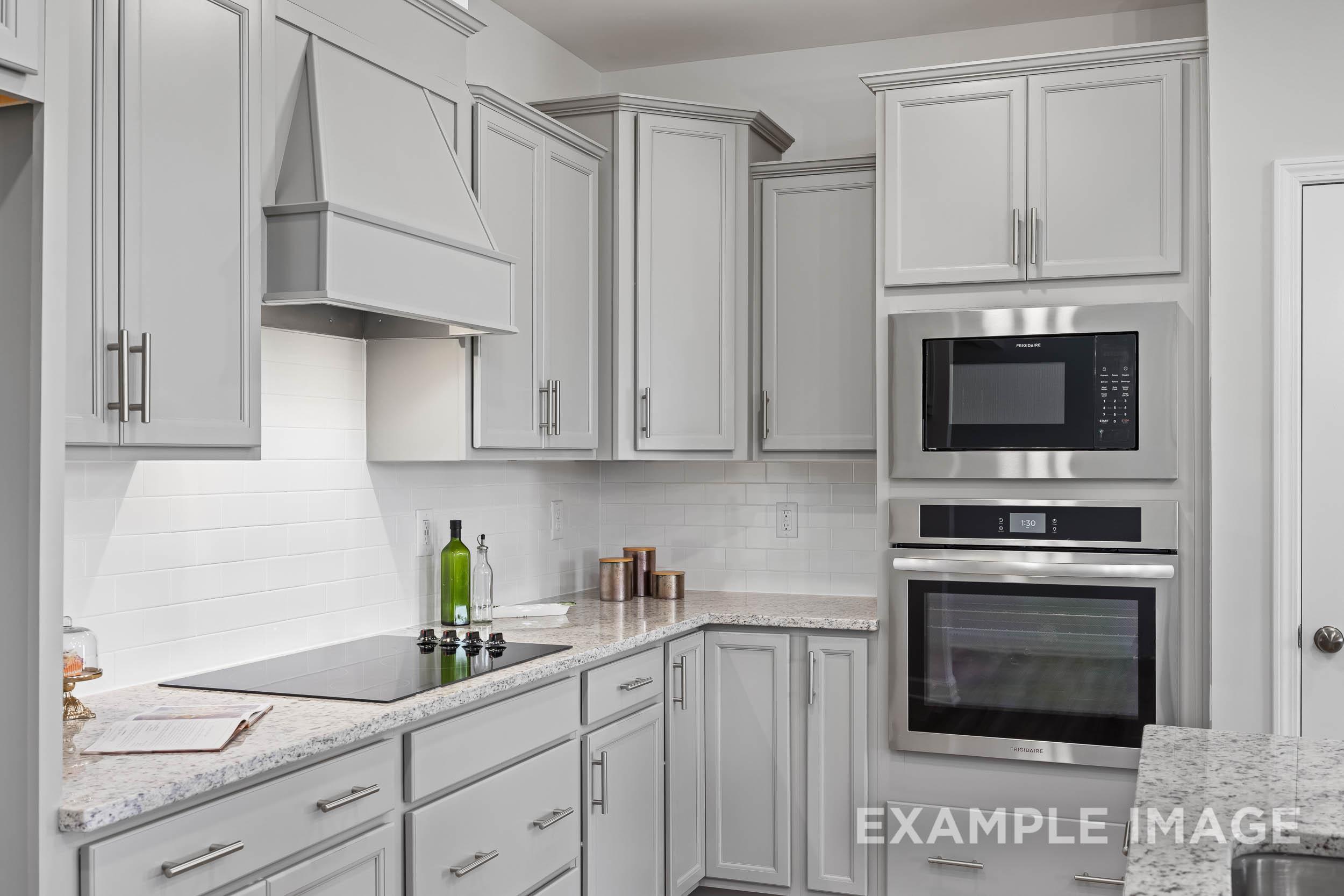 Modern kitchen in The Daphne C by Davidson Homes featuring white shaker cabinets, stainless steel double oven, and quartz counters
