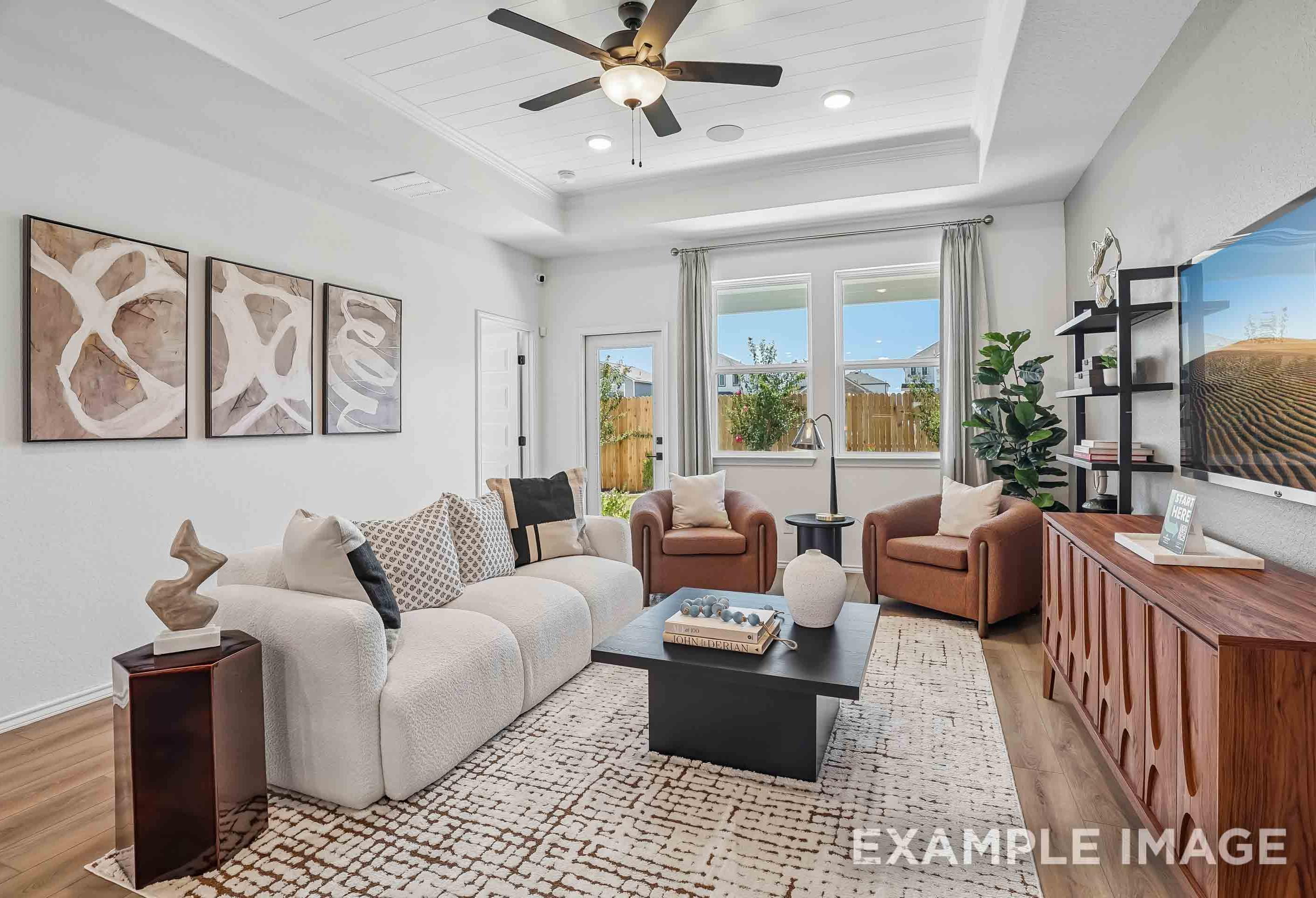 Modern living room in The Pinecrest B featuring a tray ceiling, plush sofa, and stylish decor in a San Antonio home.