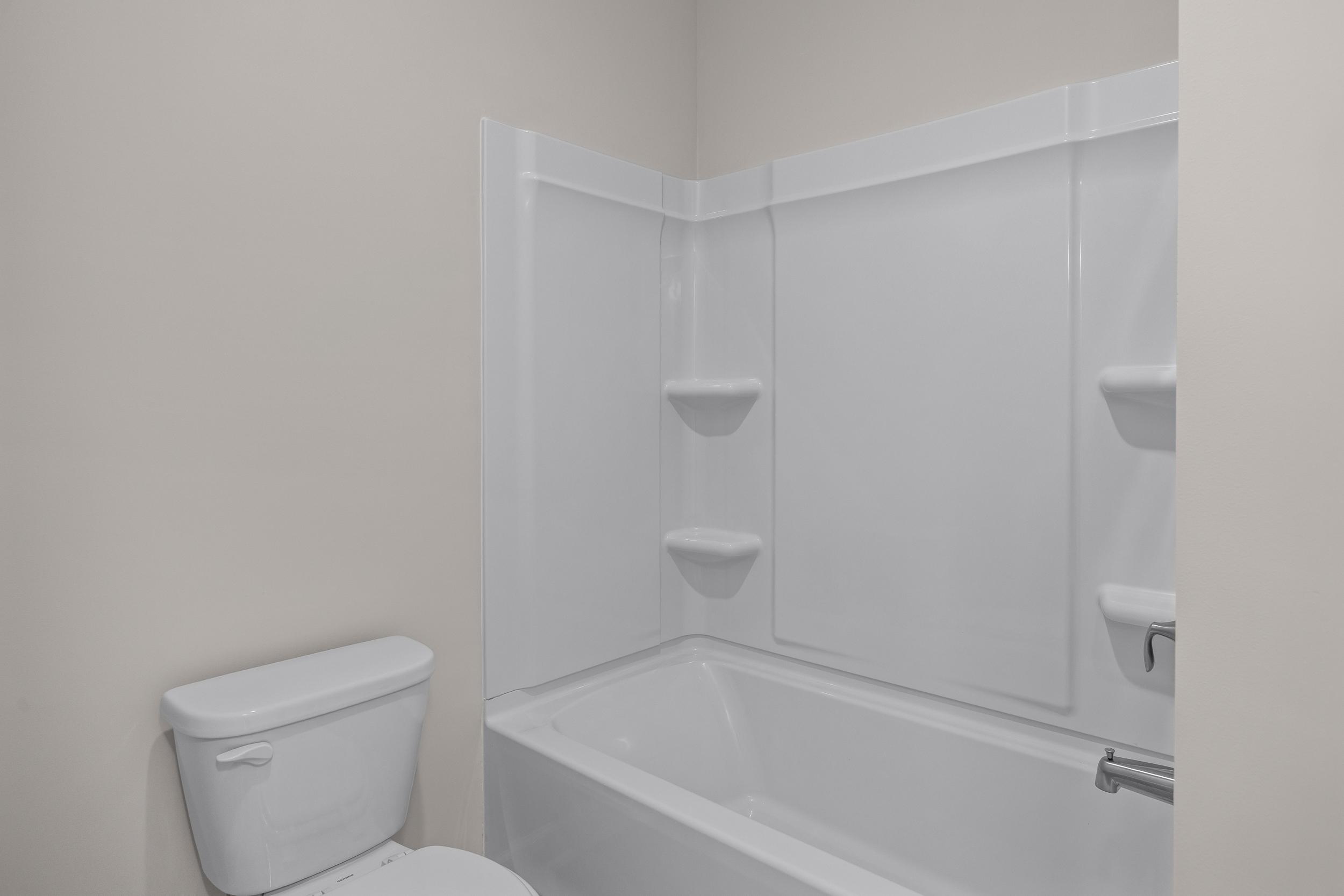 Contemporary secondary bathroom in The Aspen Davidson Homes design: white tub-shower combo with shelves and toilet