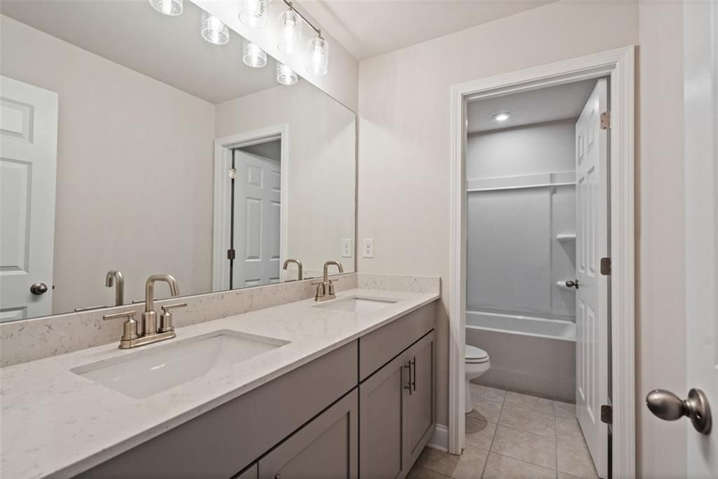 Modern master bathroom featuring double vanity with gray cabinets and subway tile shower in Davidson Homes The Hickory B, Hoschton, GA