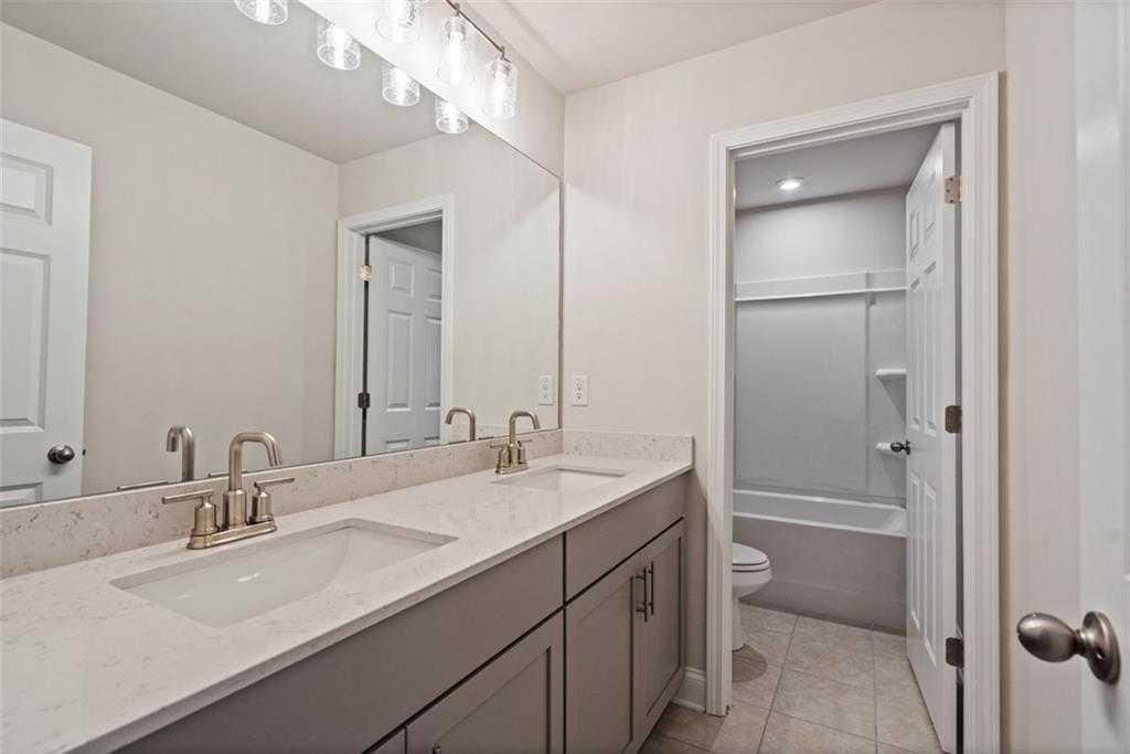 Modern master bathroom featuring double vanity with gray cabinets and subway tile shower in Davidson Homes The Hickory B, Hoschton, GA
