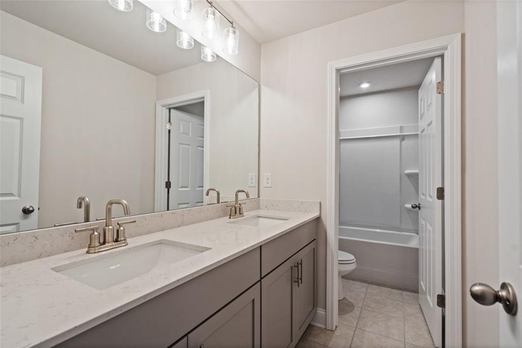 Modern master bathroom featuring double vanity with gray cabinets and subway tile shower in Davidson Homes The Hickory B, Hoschton, GA