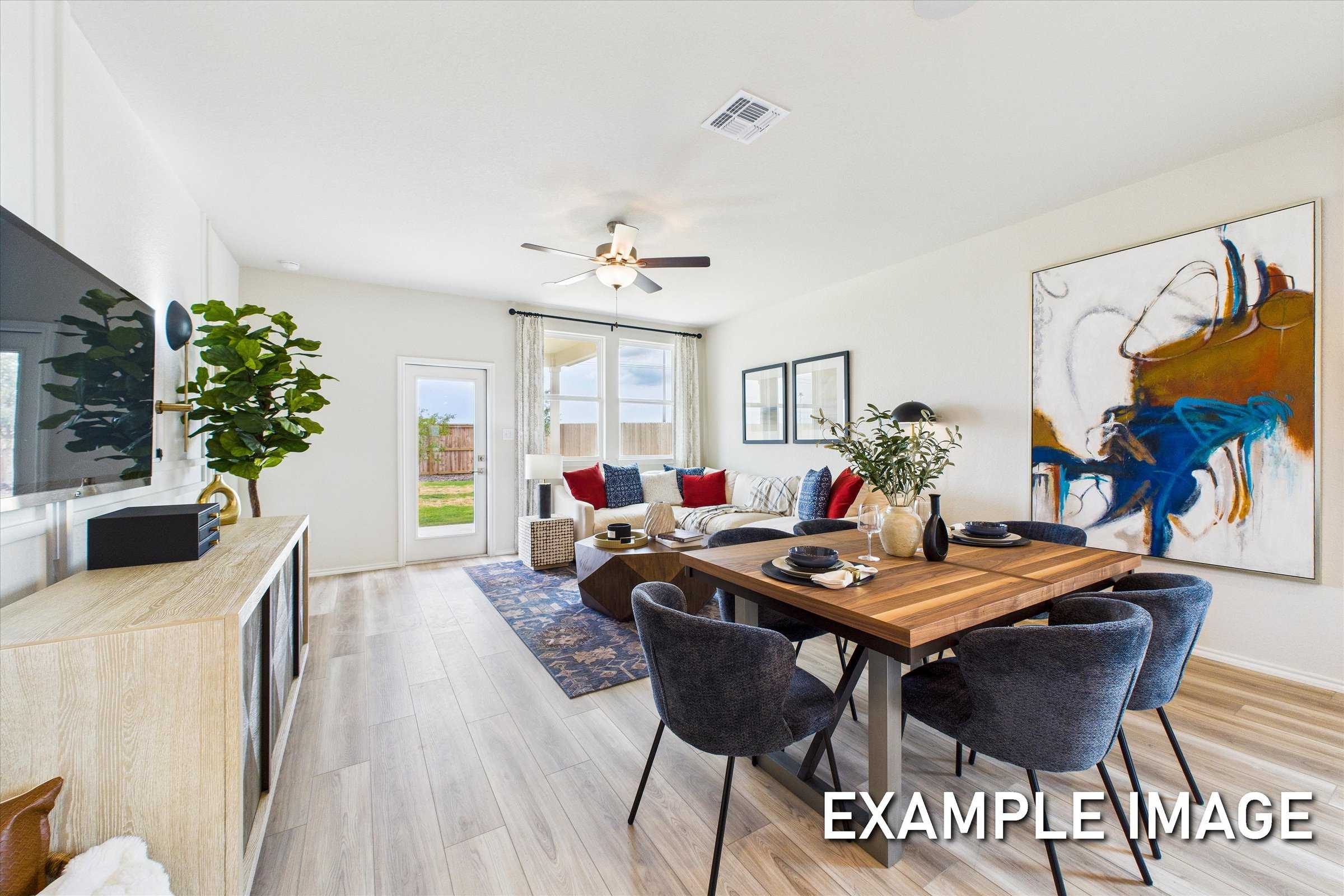 Modern open living and dining area with wooden table, velvet chairs, mounted TV, abstract wall art, and garden views in Davidson Homes The Brazos C, San Antonio