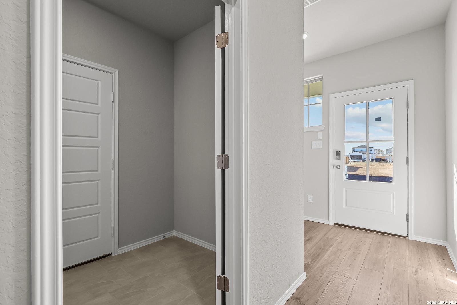 Neutral-toned hallway with white doors and glass-paneled entry to outdoors in Davidson Homes The Frio B, Applewhite Meadows, San Antonio