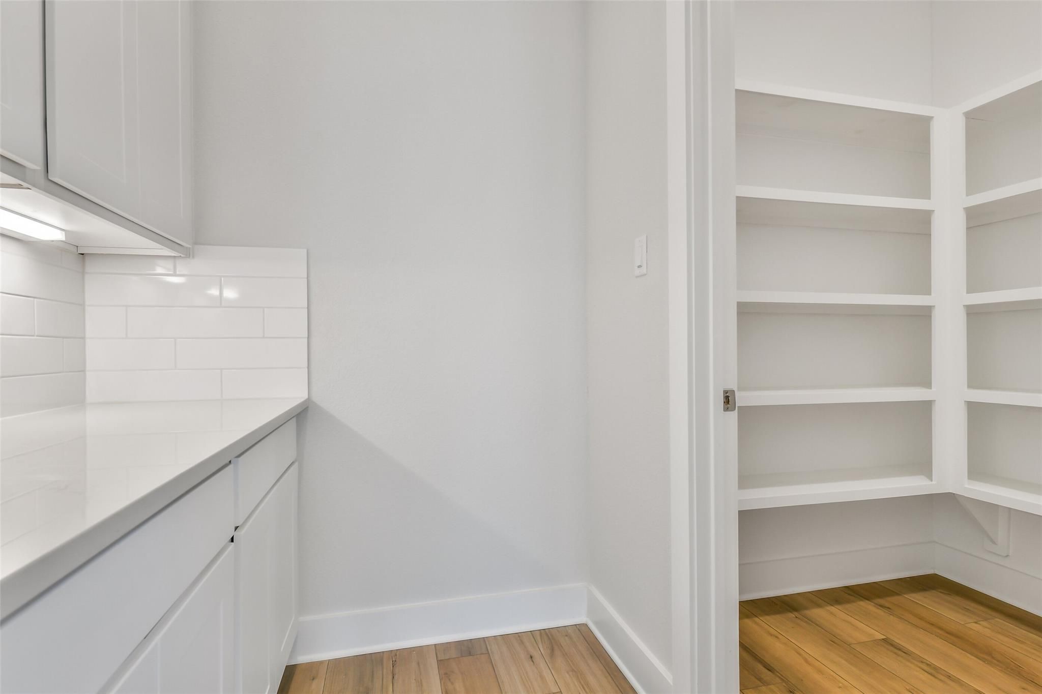 Modern white kitchen featuring quartz counters, subway tile backsplash, and adjacent walk-in pantry in Davidson Homes The Victoria A, Lago Mar