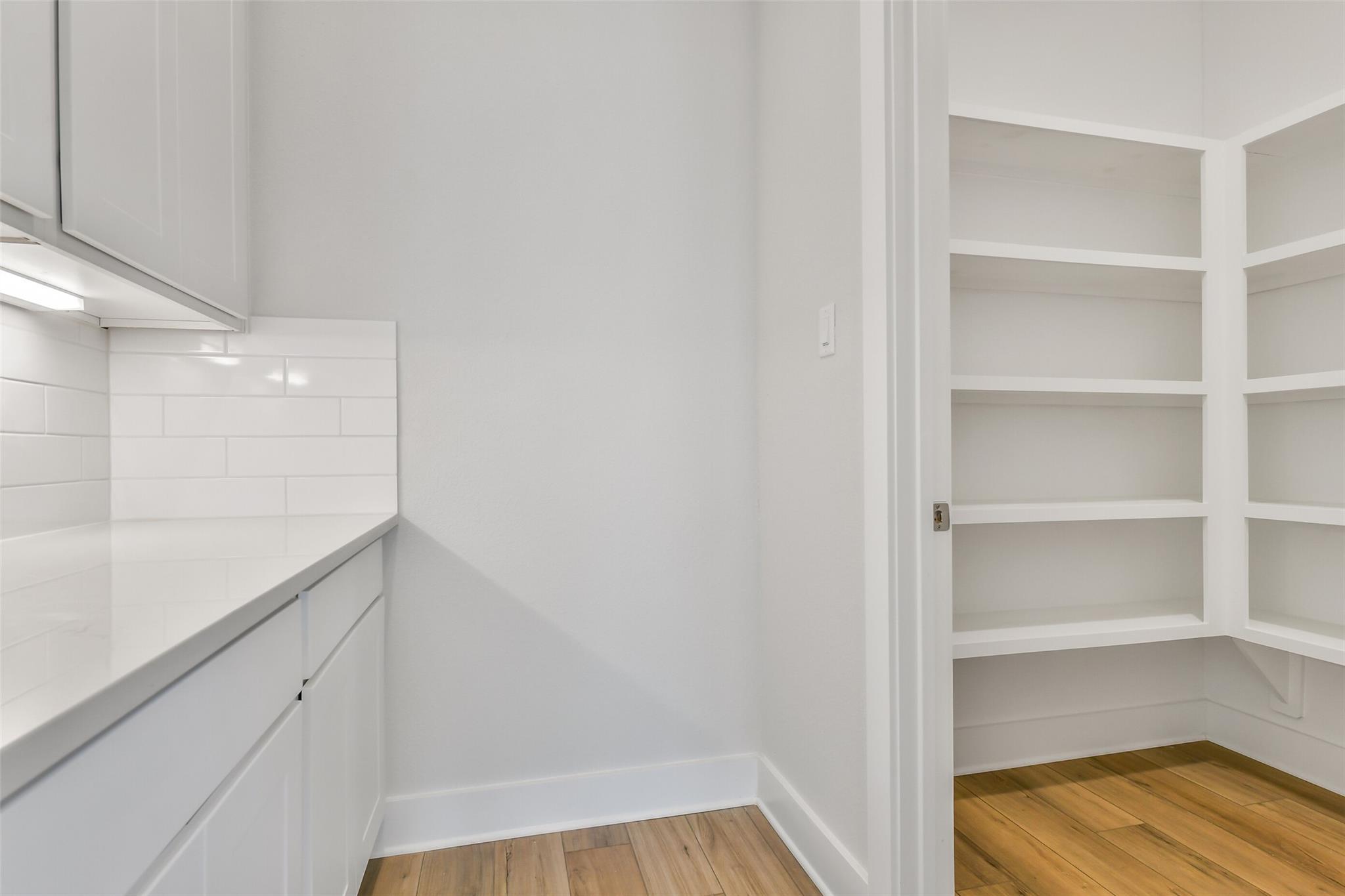 Modern white kitchen featuring quartz counters, subway tile backsplash, and adjacent walk-in pantry in Davidson Homes The Victoria A, Lago Mar