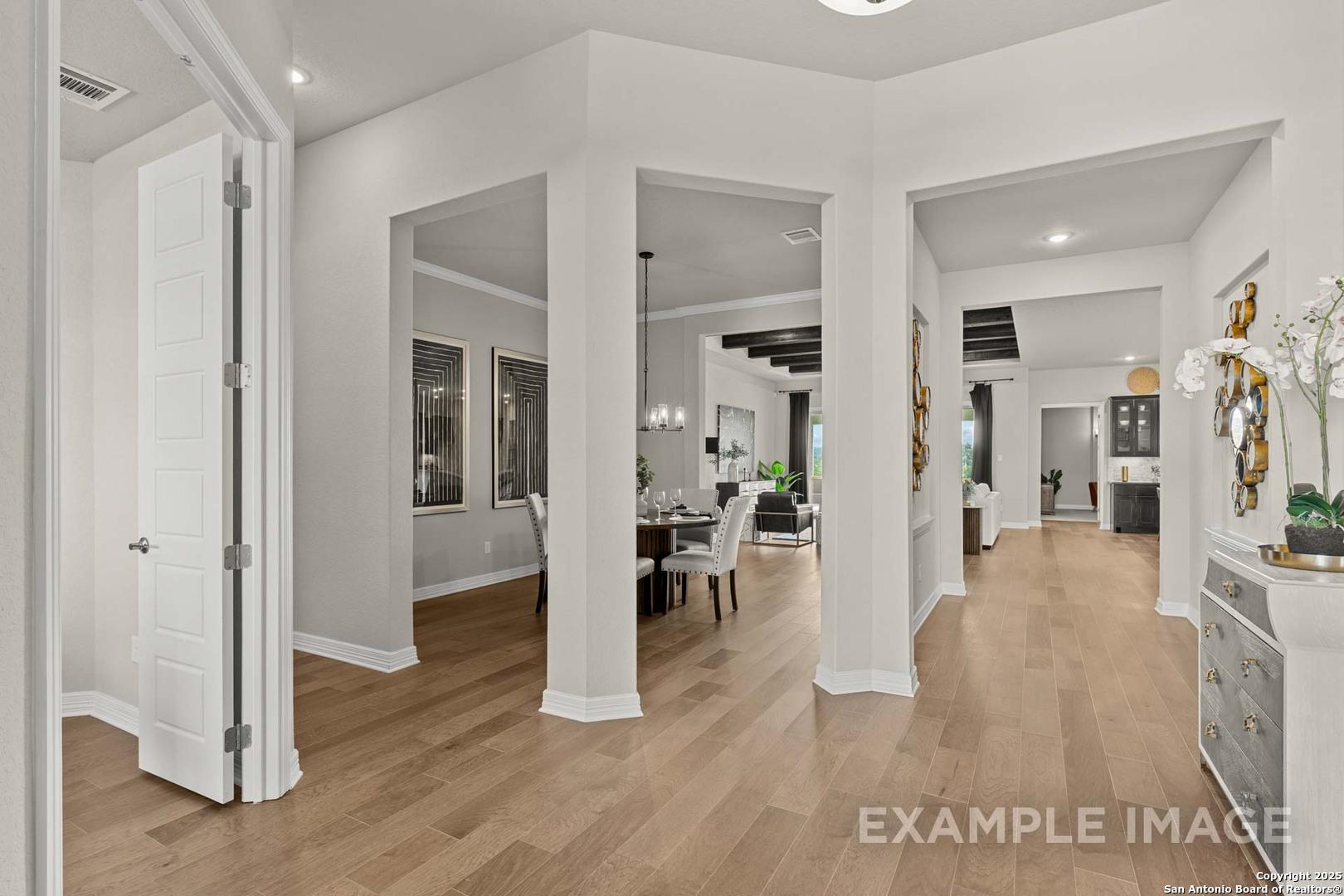 Open dining area with archways, wooden table, chairs, and hardwood floors in Davidson Homes The Summerlin B, Castroville, Texas