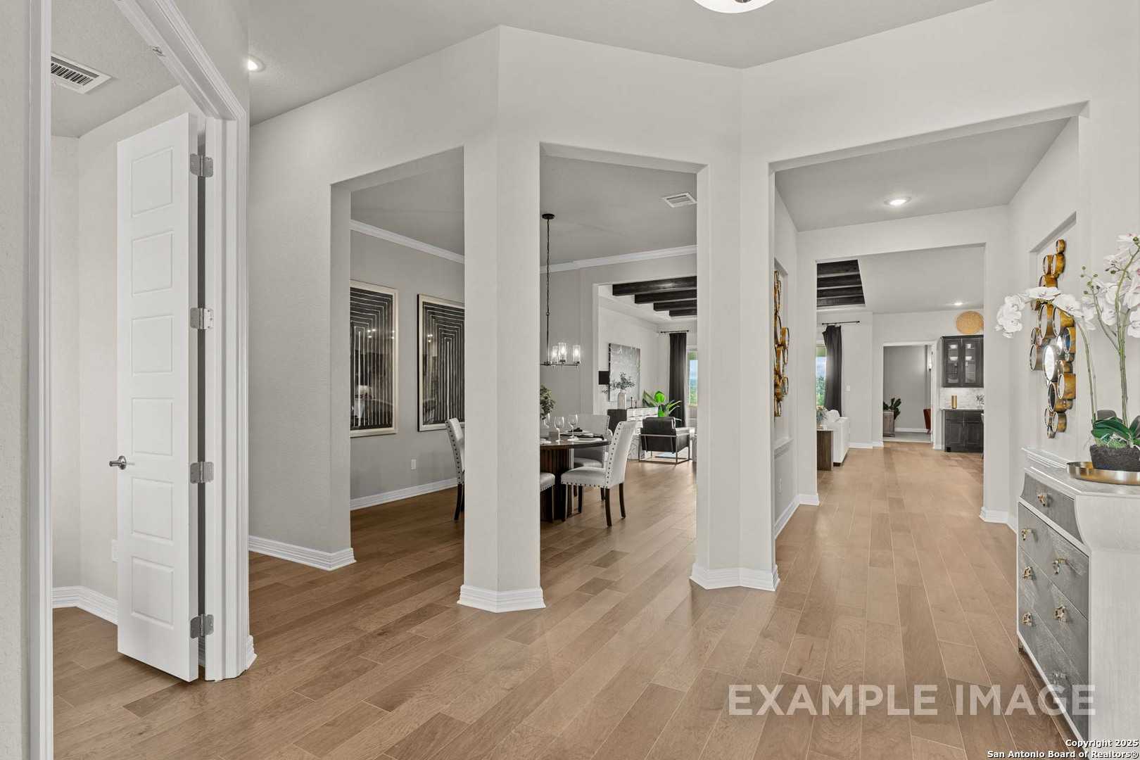 Open dining area with archways, wooden table, chairs, and hardwood floors in Davidson Homes The Summerlin B, Castroville, Texas