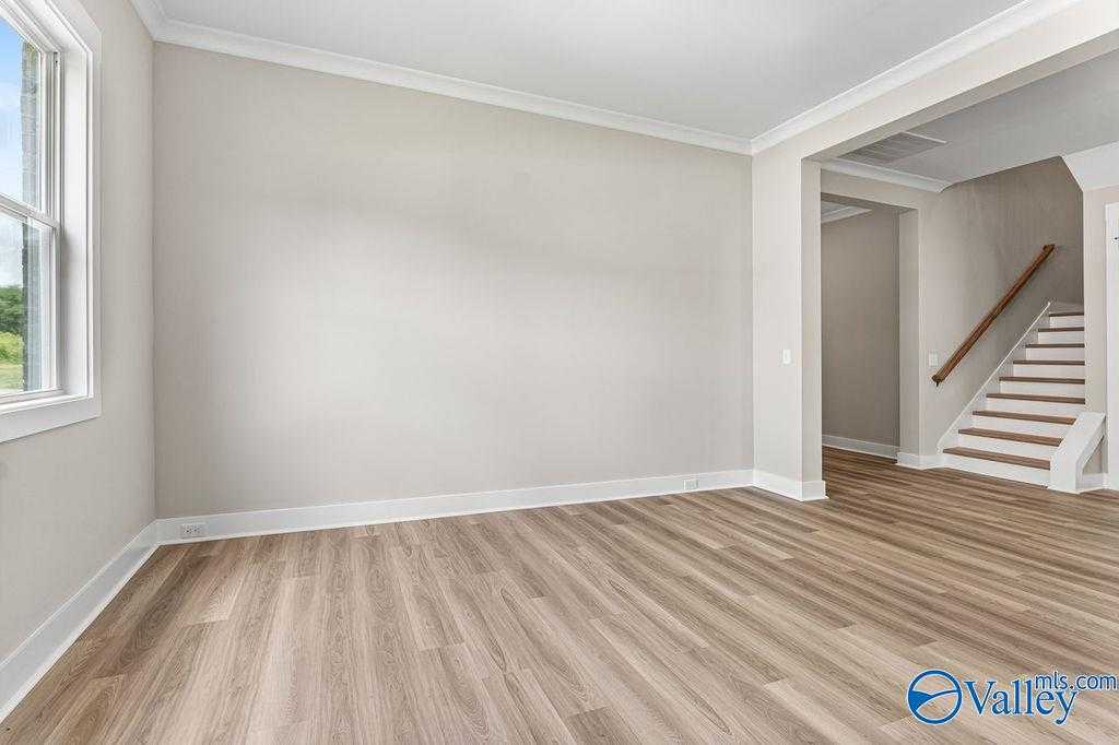 Spacious foyer with light oak hardwood floors, arched opening to oak staircase in Evermore Homes The Oxford, Owens Cross Roads, Alabama