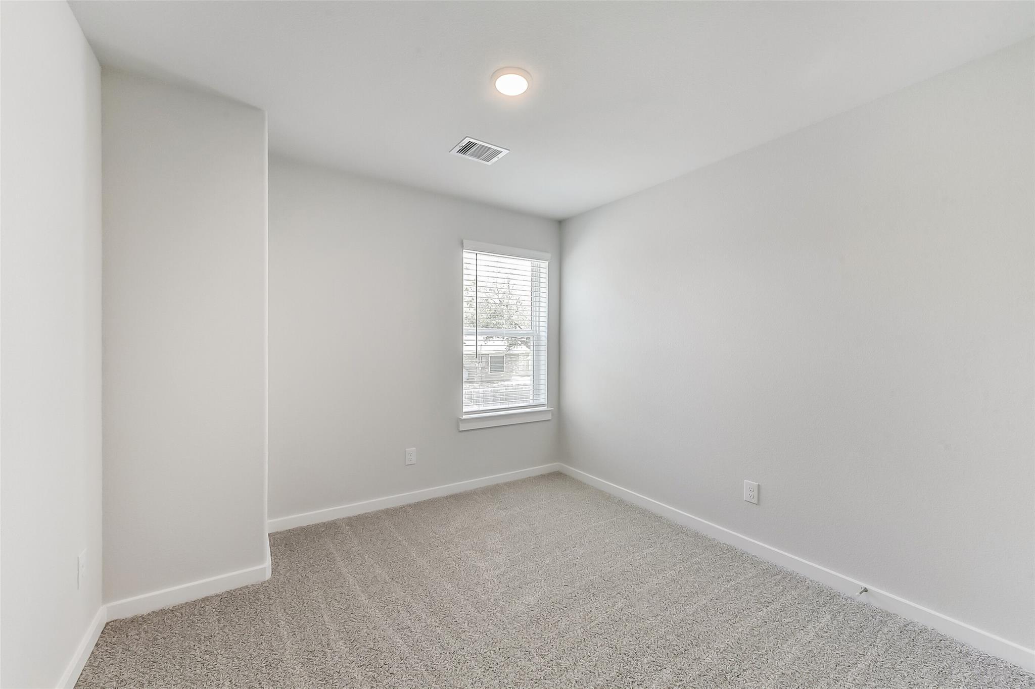 Bright secondary bedroom with gray walls, beige carpet, and window blinds in Davidson Homes The Brazos E, Magnolia, Texas