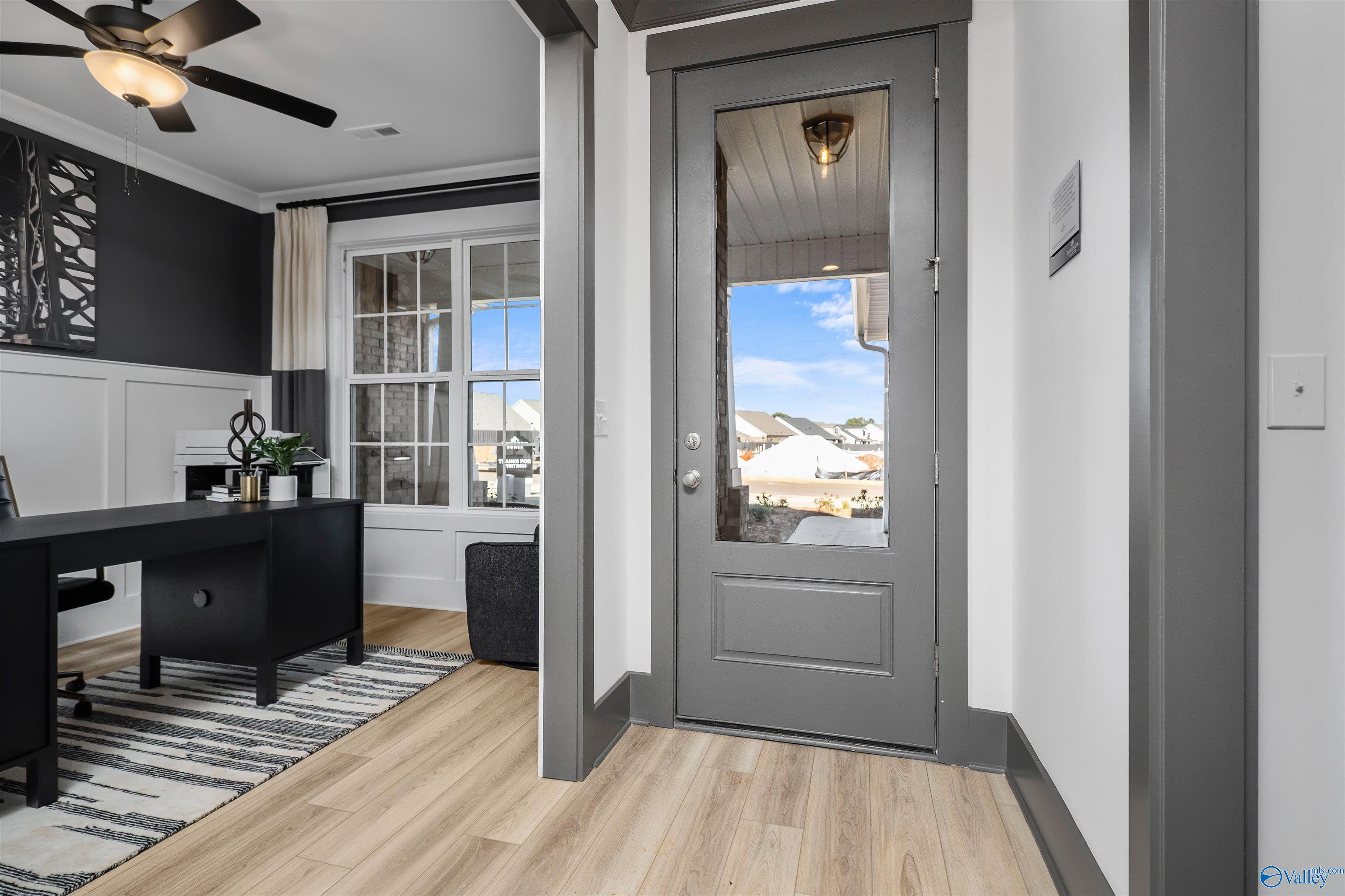 Elegant home office with wooden desk, ceiling fan, and glass door to outdoor view in Davidson Homes The Rockford B, Madison, Alabama