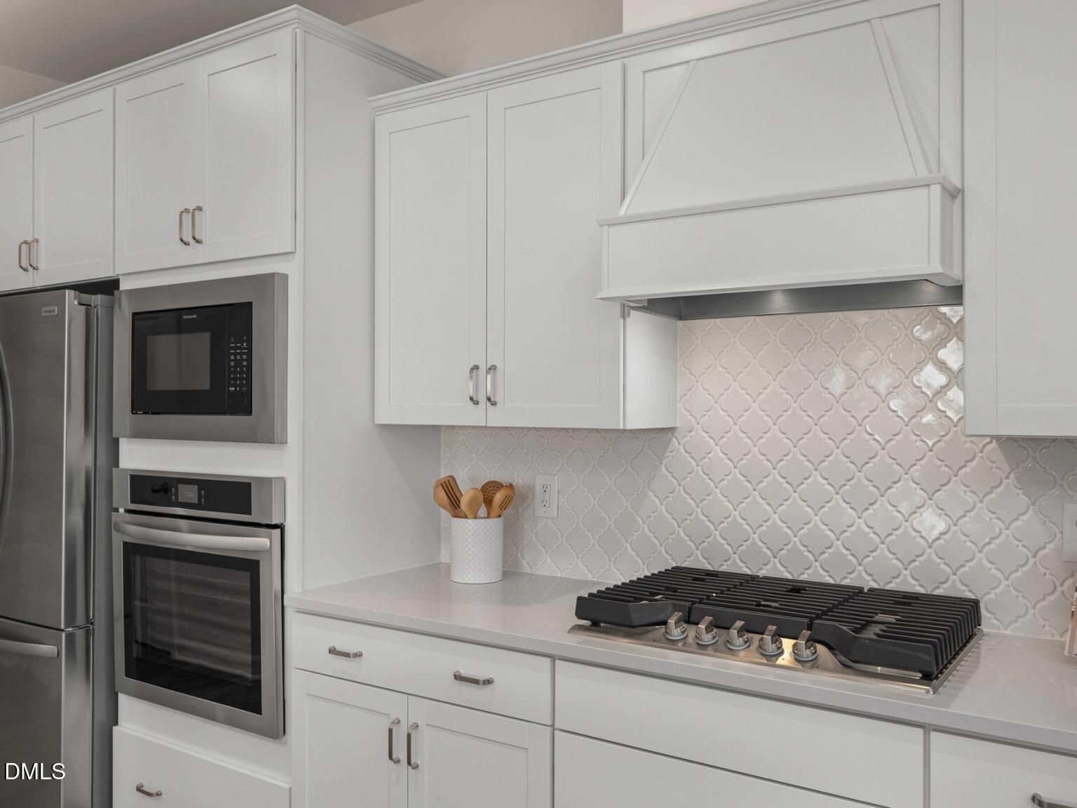 Modern white kitchen with stainless steel appliances, subway tile backsplash, and gas cooktop in Davidson Homes Hickory II D, Wake Forest, NC