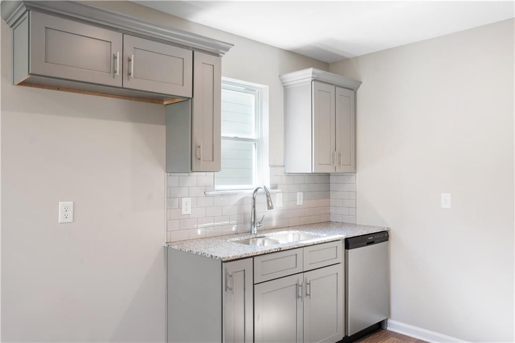 Modern kitchen featuring gray shaker cabinets, granite counters, subway tile backsplash in Davidson Homes The Washington, Phenix City, AL