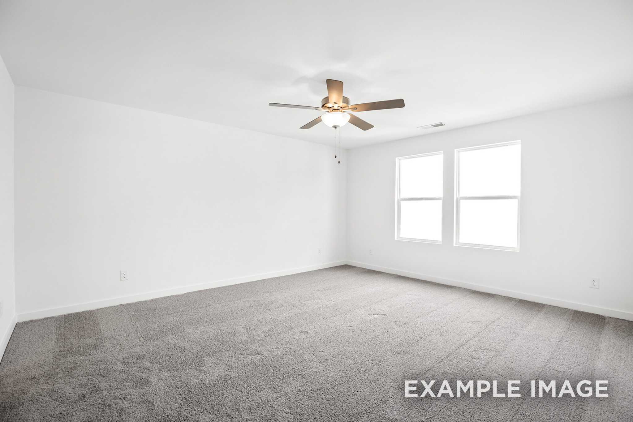 Spacious empty bedroom in The Murray B with white walls, ceiling fan light, double windows, and gray carpet