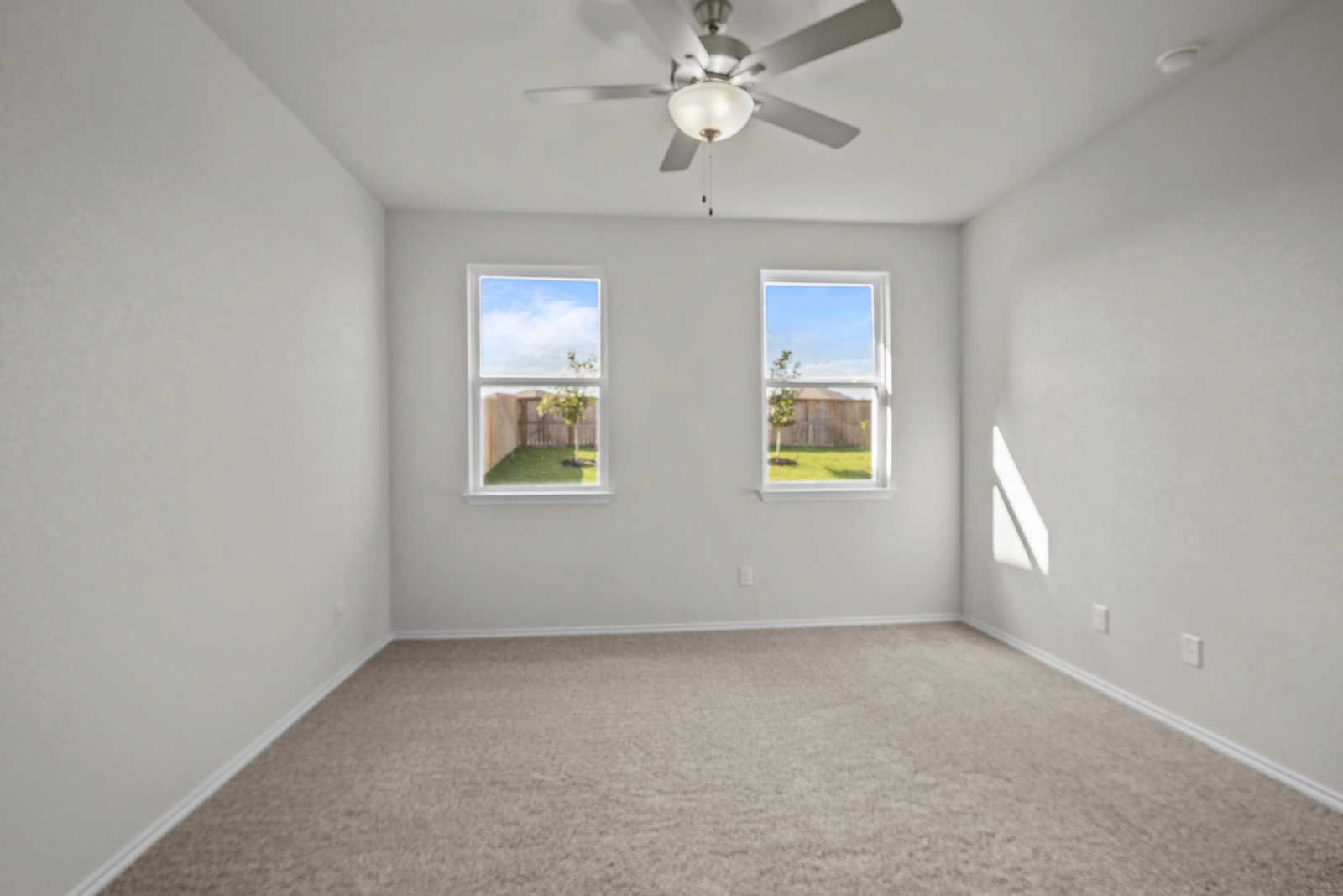 Bright secondary bedroom with ceiling fan and large windows overlooking green yard in Davidson Homes The Redbud B, Josephine, Texas