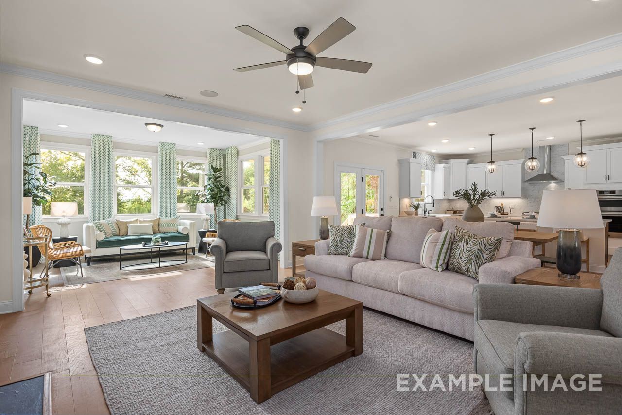 Open-concept living room and kitchen at Wendell Ridge in Wendell, NC by Davidson Homes with hardwood floors, neutral sofas, and large windows
