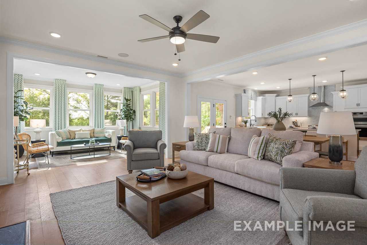 Open-concept living room and kitchen at Wendell Ridge in Wendell, NC by Davidson Homes with hardwood floors, neutral sofas, and large windows