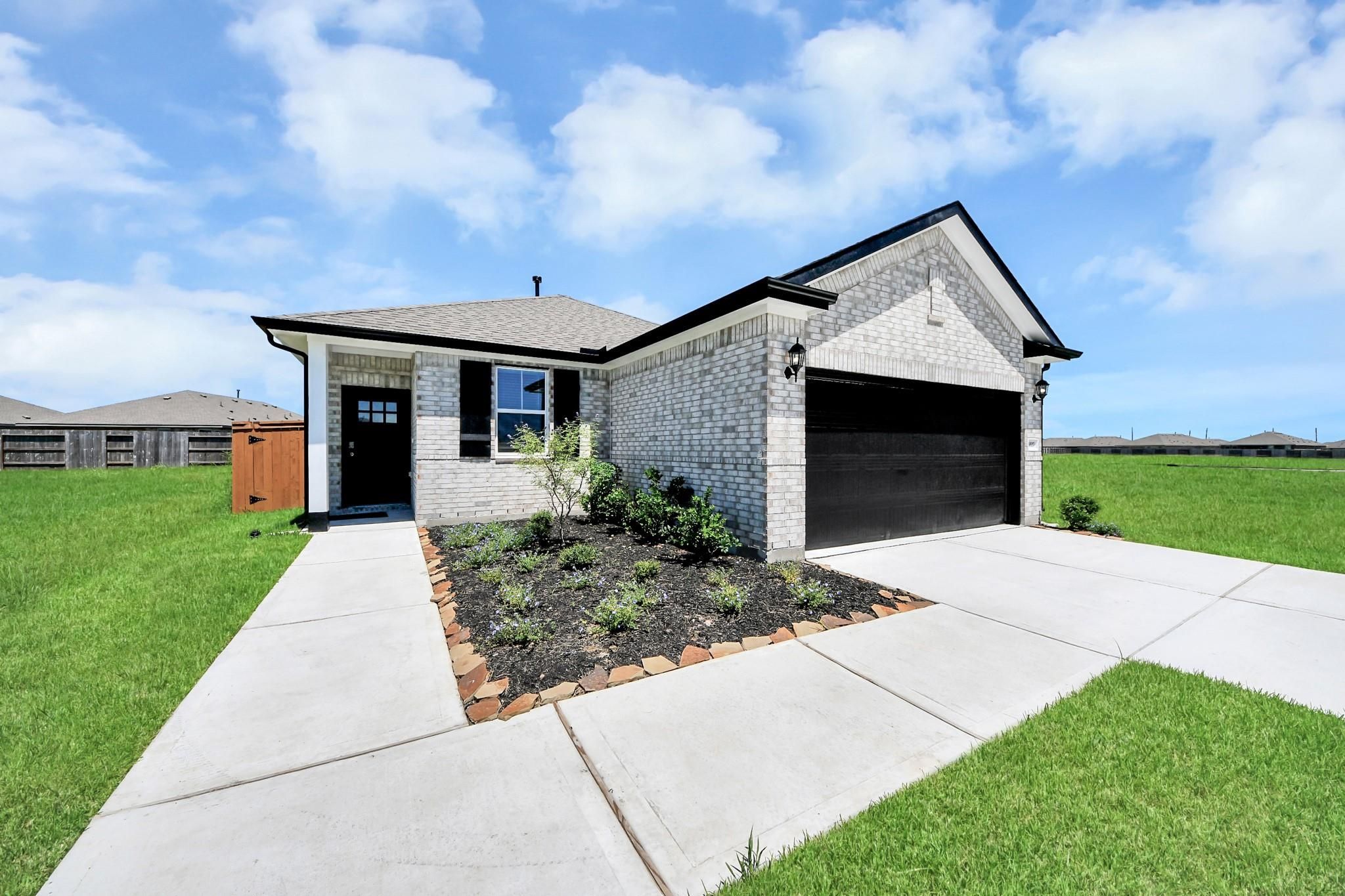 White brick exterior with black garage door and landscaped yard of The Costa A, a 3-bedroom Davidson Homes plan in Beasley, Texas