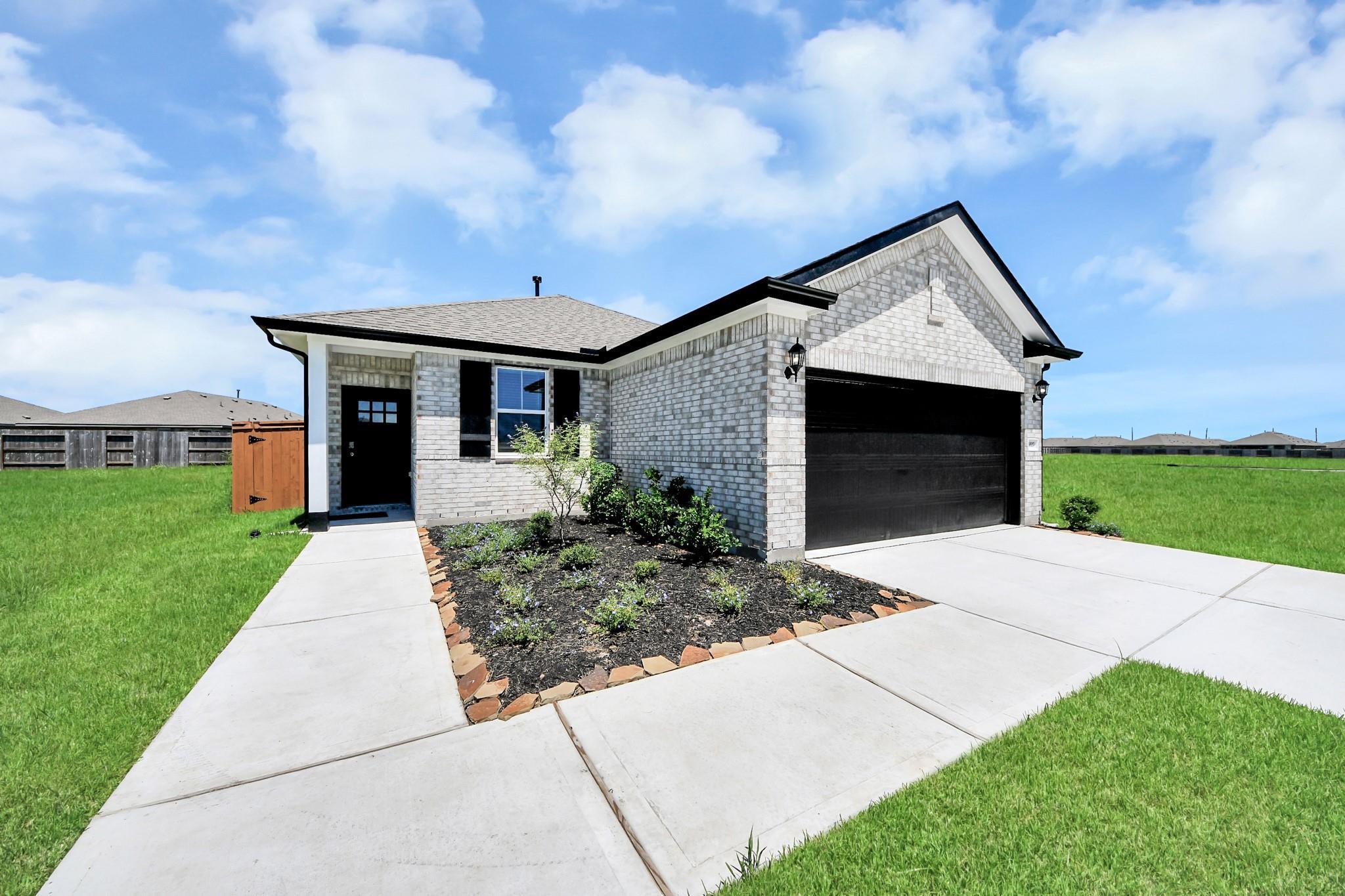 White brick exterior with black garage door and landscaped yard of The Costa A, a 3-bedroom Davidson Homes plan in Beasley, Texas