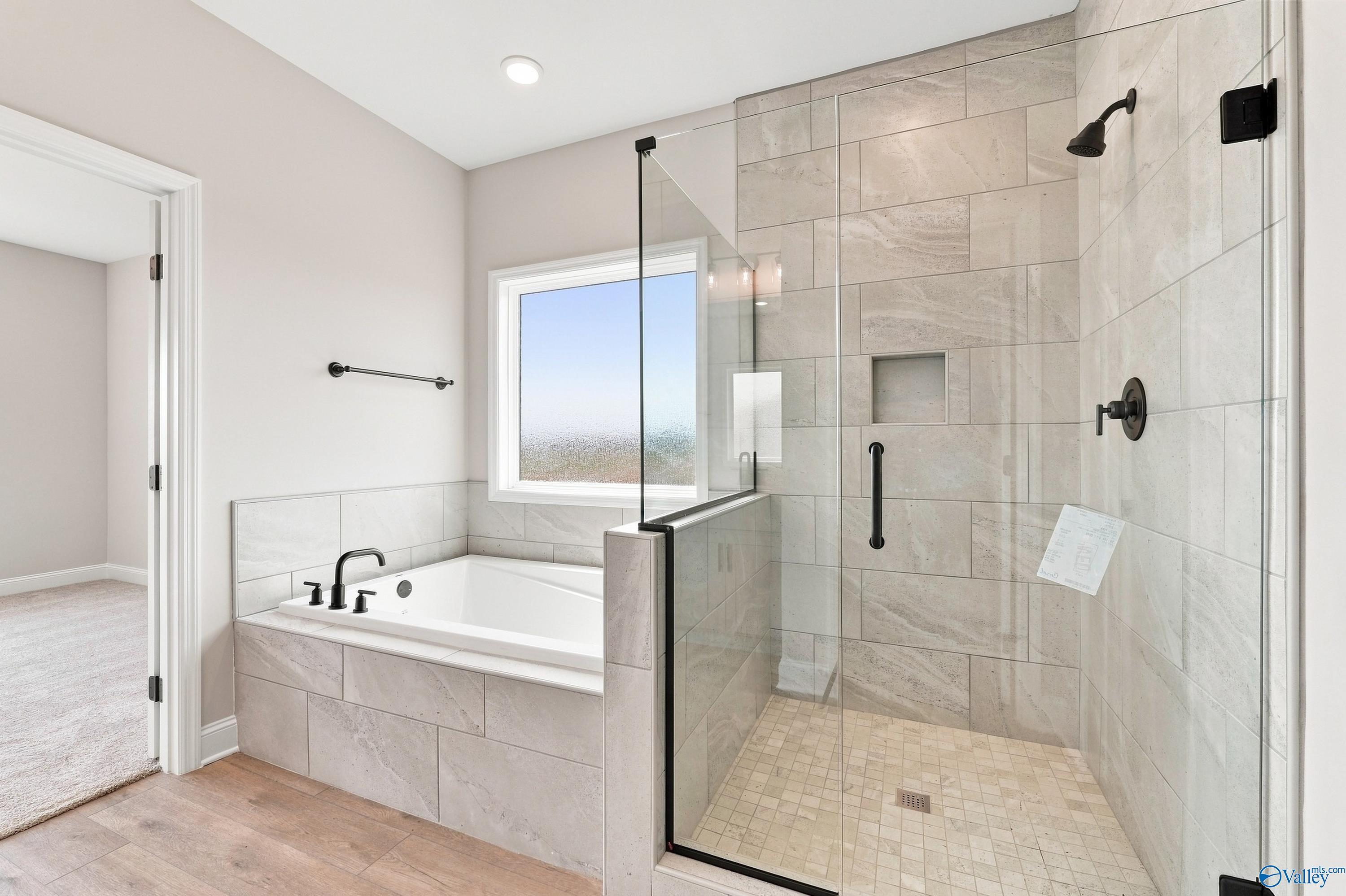 Modern master bathroom with garden tub, glass walk-in shower, and black fixtures in Davidson Homes Montgomery D, Athens, Alabama