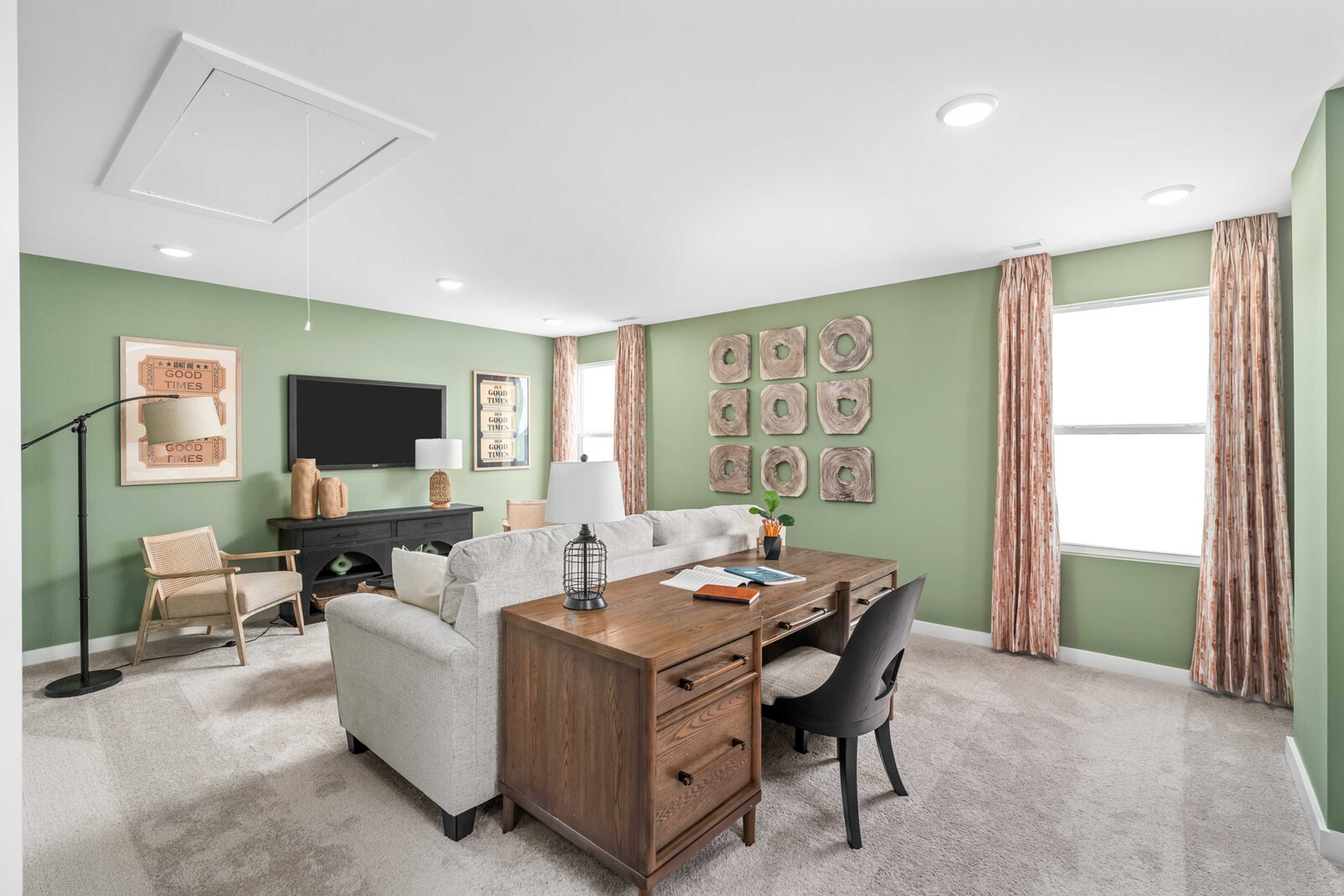 Spacious home office in Calista Farms, White House TN with wooden desk, mounted TV, sage green walls and sofa