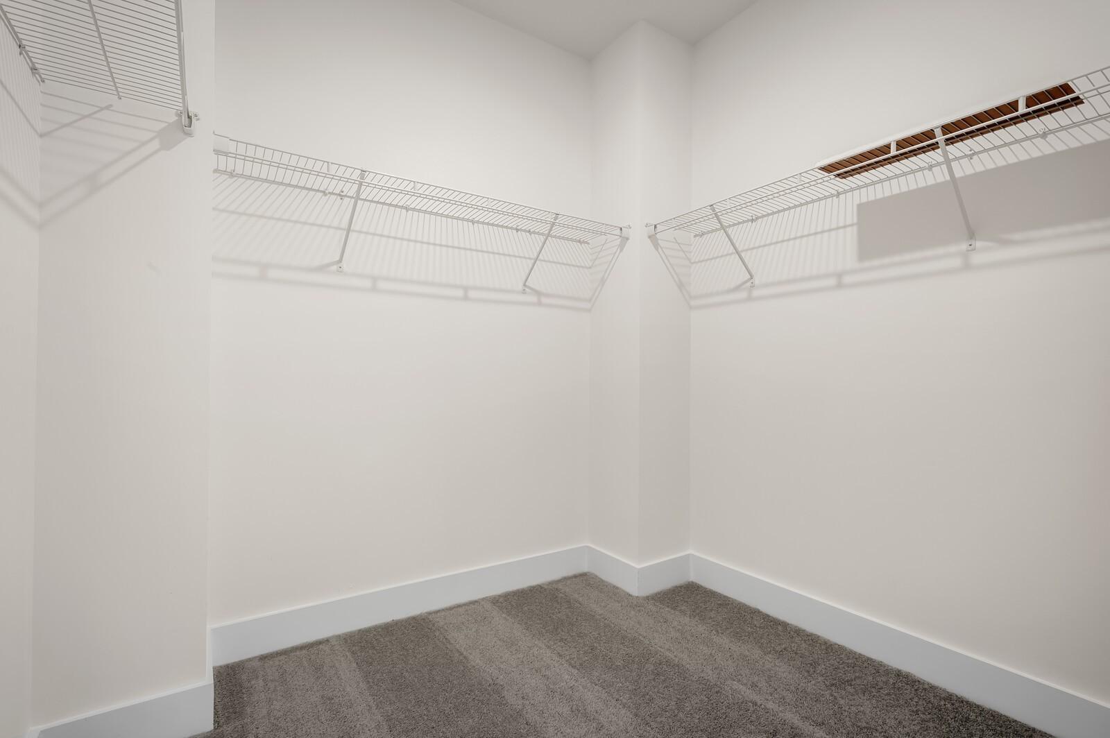 Walk-in closet with white wire shelving and carpeted floors in The Ash A floor plan at Woods Crossing, Gallatin, TN.