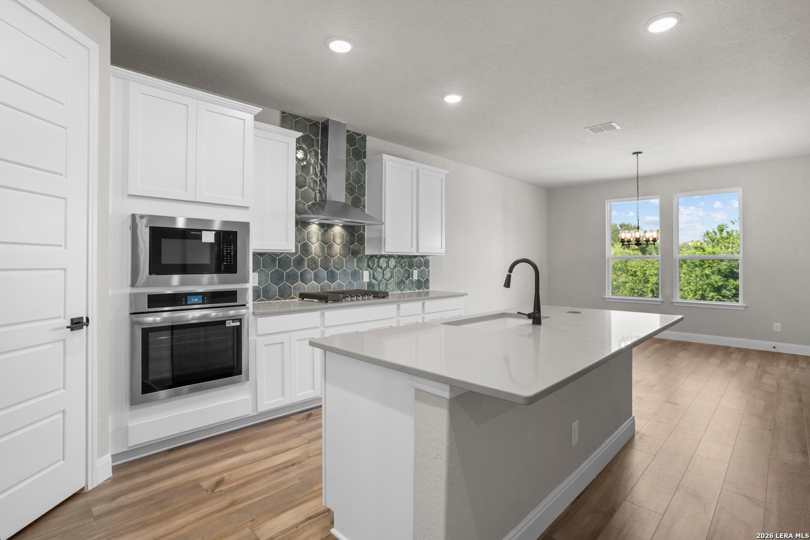 Modern kitchen with white cabinets, quartz island, and tile backsplash in The Jennings G plan at Ladera, San Antonio.