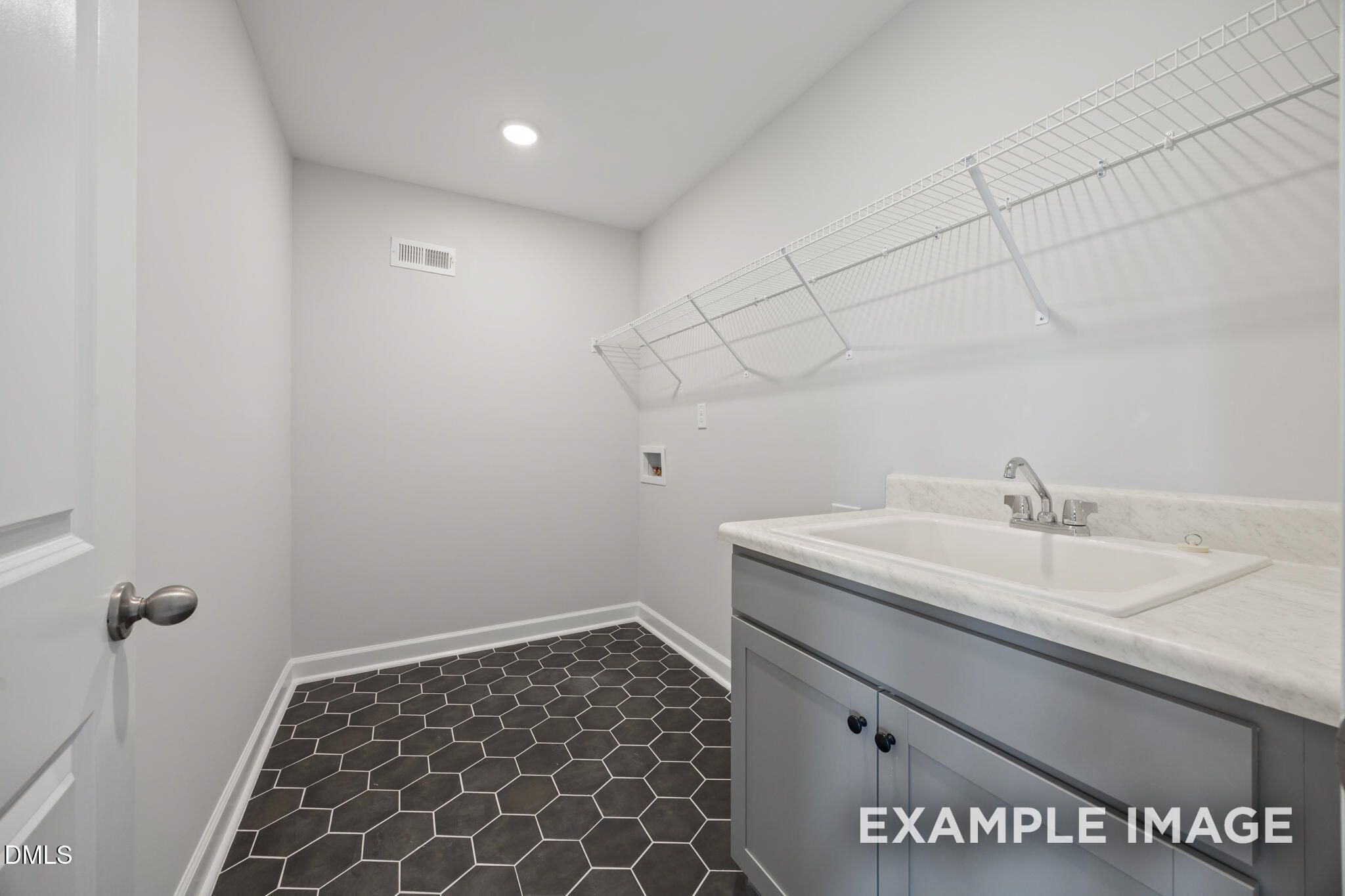 Laundry room with utility sink, gray cabinetry, hexagon tile floor, and wire shelving in Davidson Homes The Beech, Wendell Ridge, NC