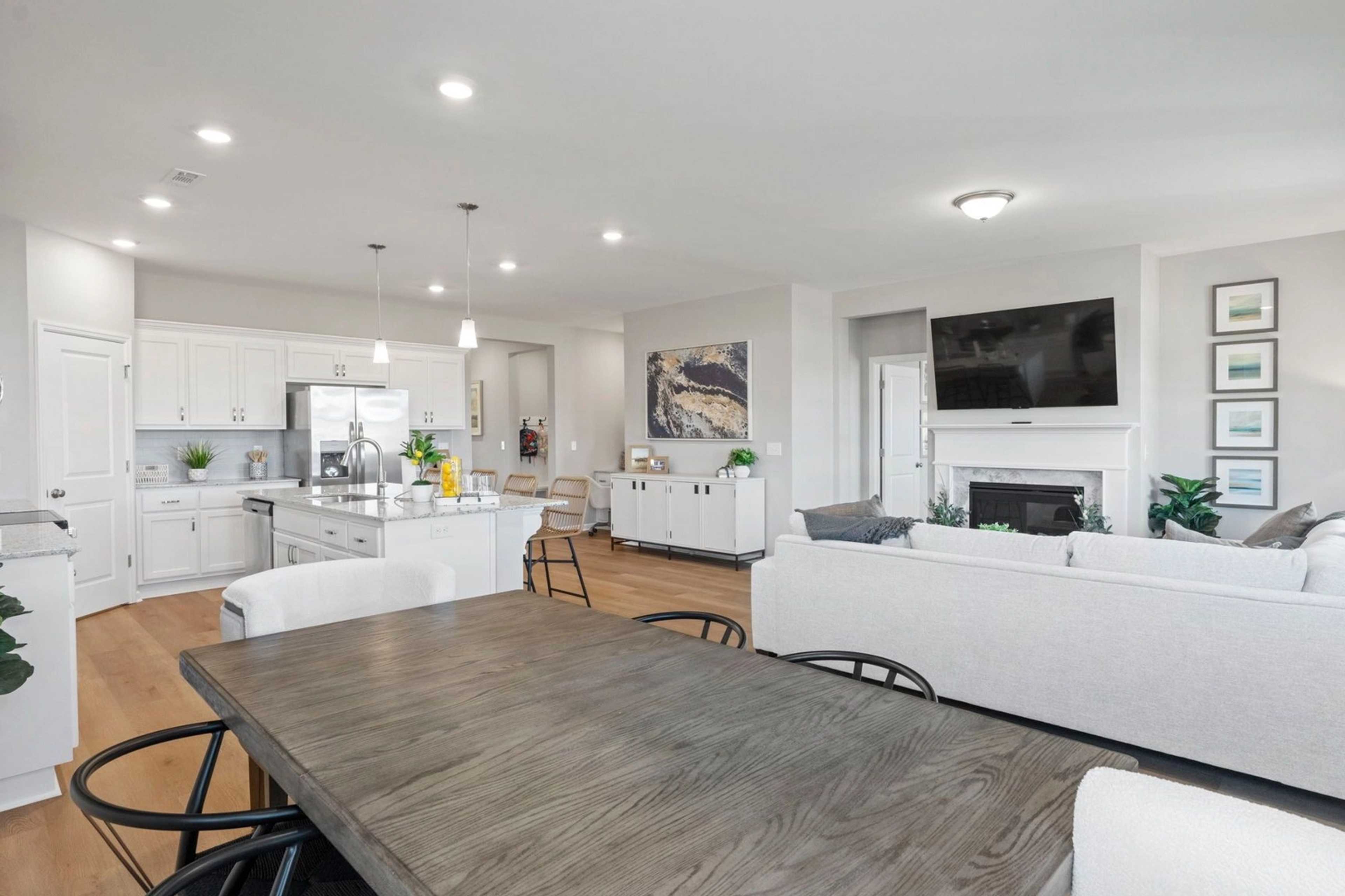 Spacious open-concept kitchen and living room at Bailey Park in Fayetteville TN with white cabinetry, hardwood floors, island bar and fireplace