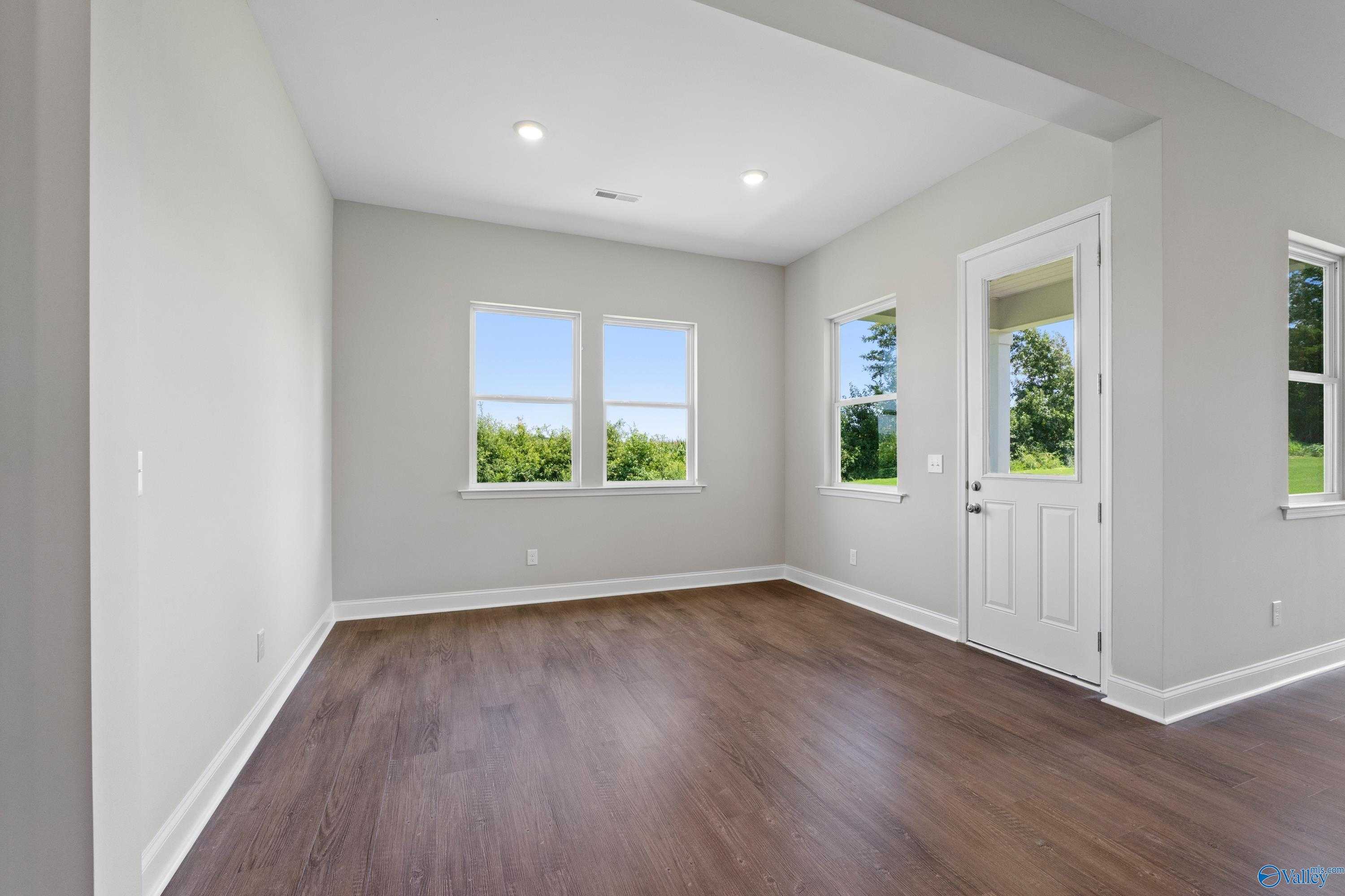 Bright sunroom with hardwood floors, light gray walls, and large windows overlooking greenery in The Arcadia, Riverton Preserve, Huntsville
