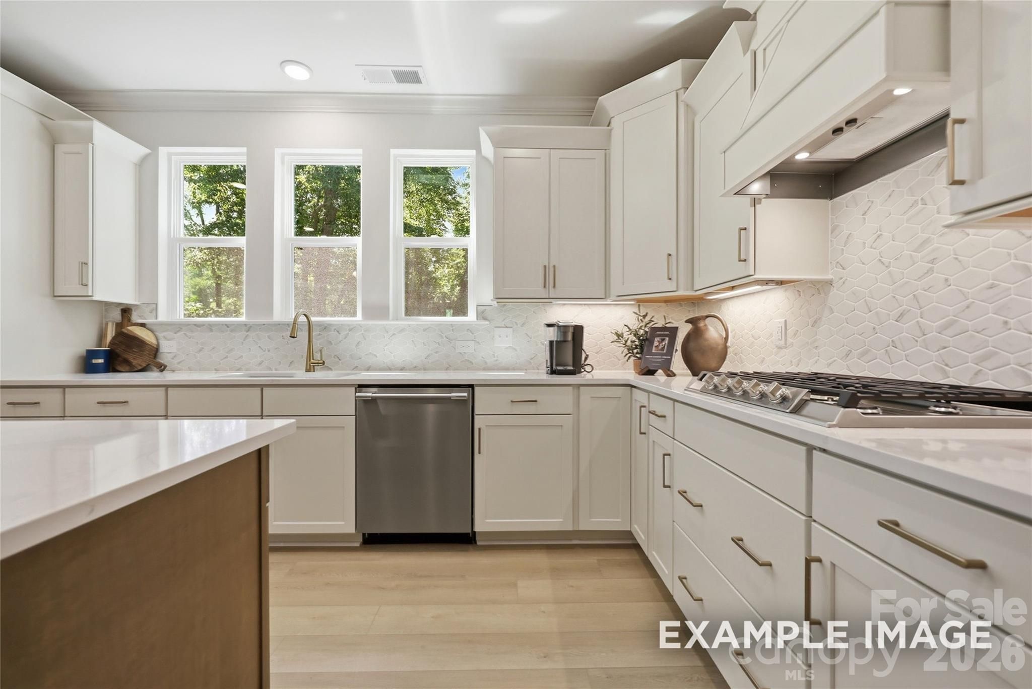 Bright white kitchen with hexagon tile backsplash, gold hardware, and stainless appliances in Davidson Homes Aspen B, Mooresville NC