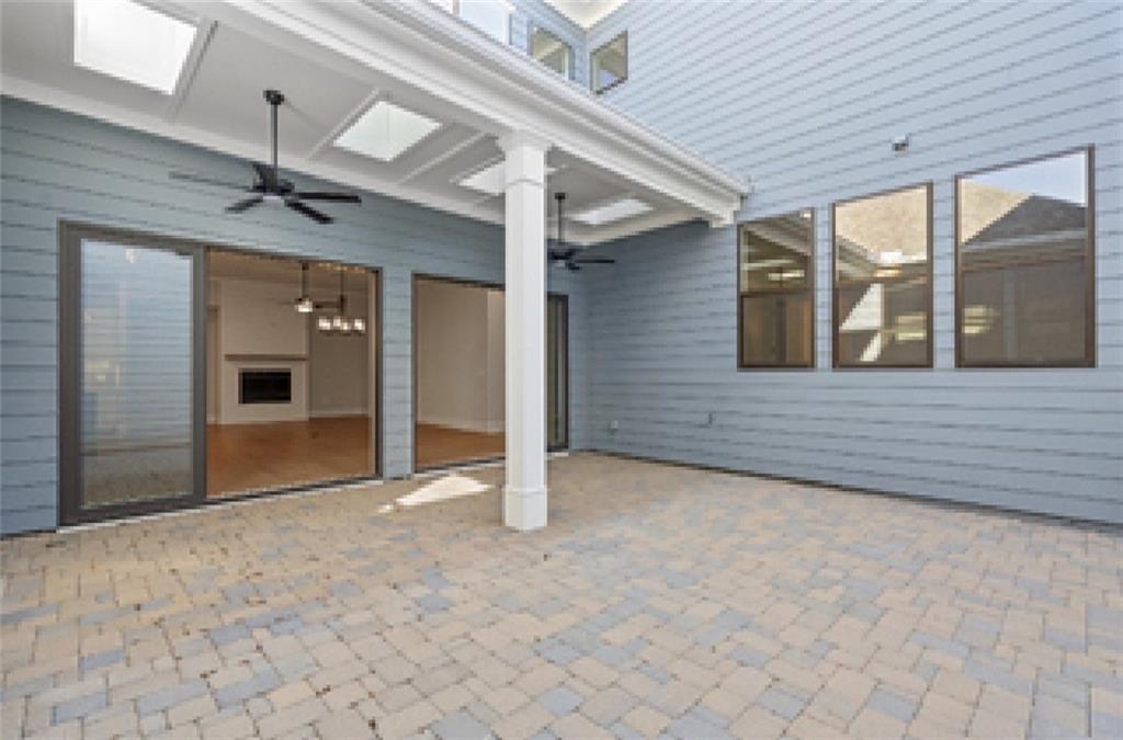 Covered patio with ceiling fans, paver floor, and glass doors to fireplace living area in Davidson Homes Seaside A, Woodstock, GA