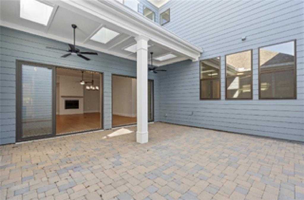 Covered patio with ceiling fans, paver floor, and glass doors to fireplace living area in Davidson Homes Seaside A, Woodstock, GA