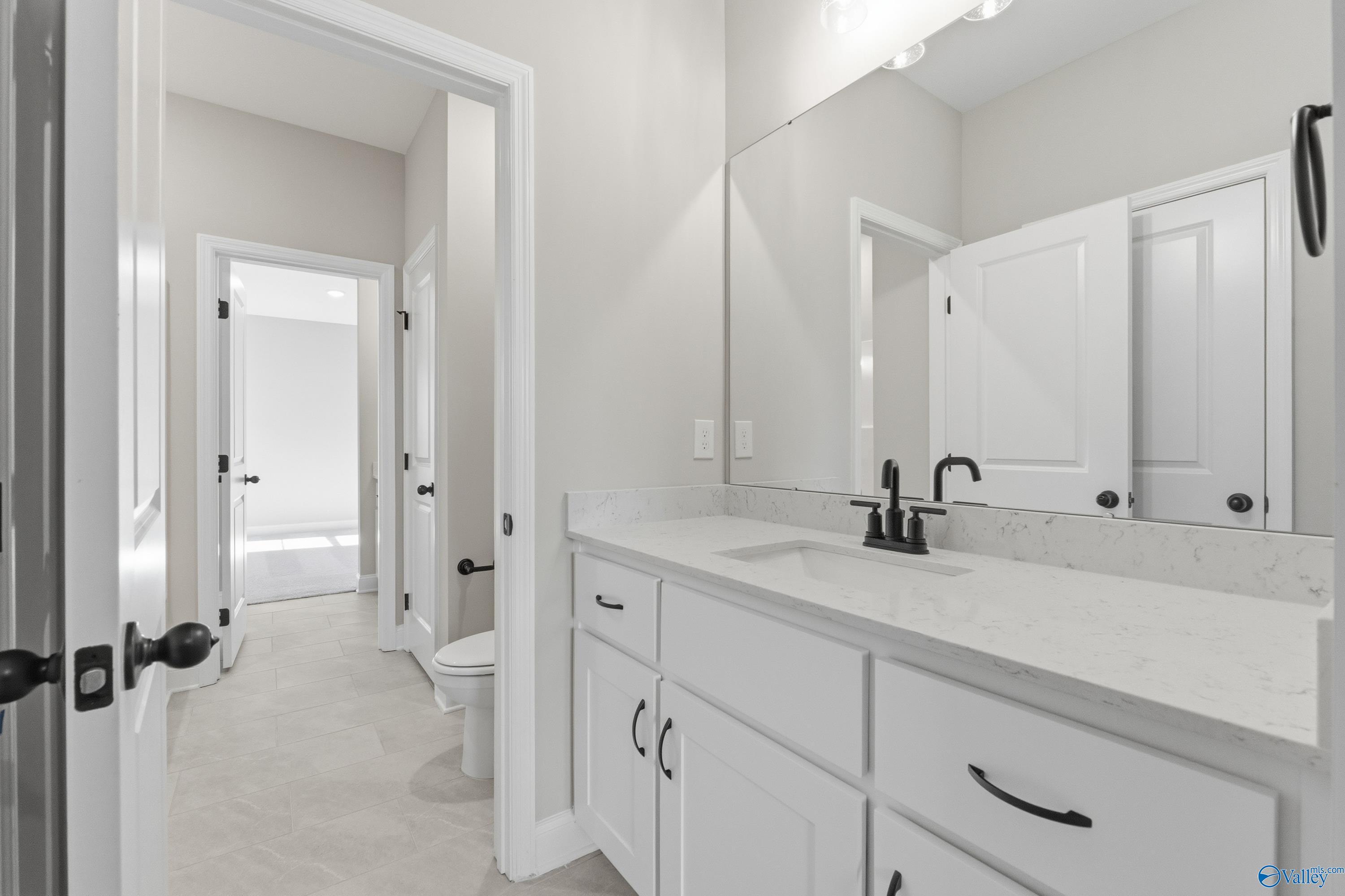 Modern master bathroom with white quartz vanity, frameless mirror, and neutral tile in Davidson Homes The Finleigh, Meridianville, Alabama