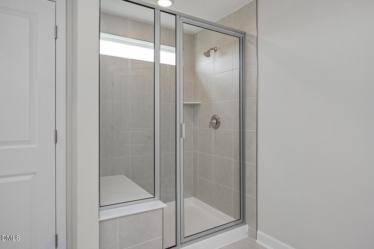 Walk-in tiled shower with built-in bench in The Graham floor plan at Springvale, Fuquay-Varina, North Carolina.