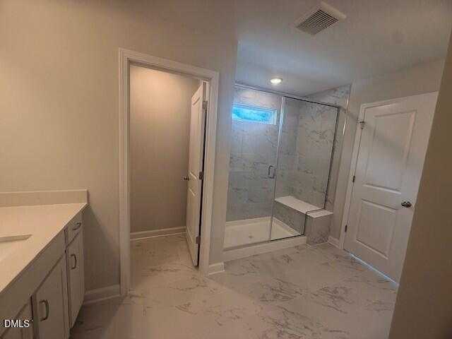 Modern master bathroom with frameless glass shower, marble-look tile floor, and white vanity in Davidson Homes The Preston C, Lillington, NC