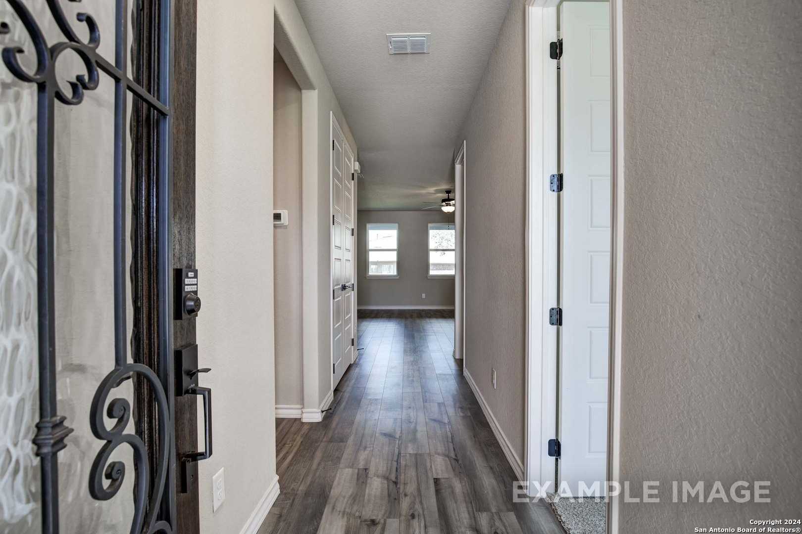 Ornate wrought iron entry door opening to spacious hallway with hardwood floors in Davidson Homes The Rockford G, Ladera, San Antonio