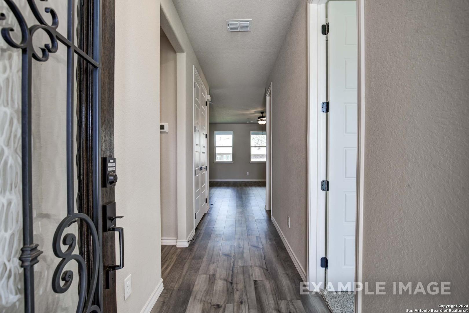 Ornate wrought iron entry door opening to spacious hallway with hardwood floors in Davidson Homes The Rockford G, Ladera, San Antonio