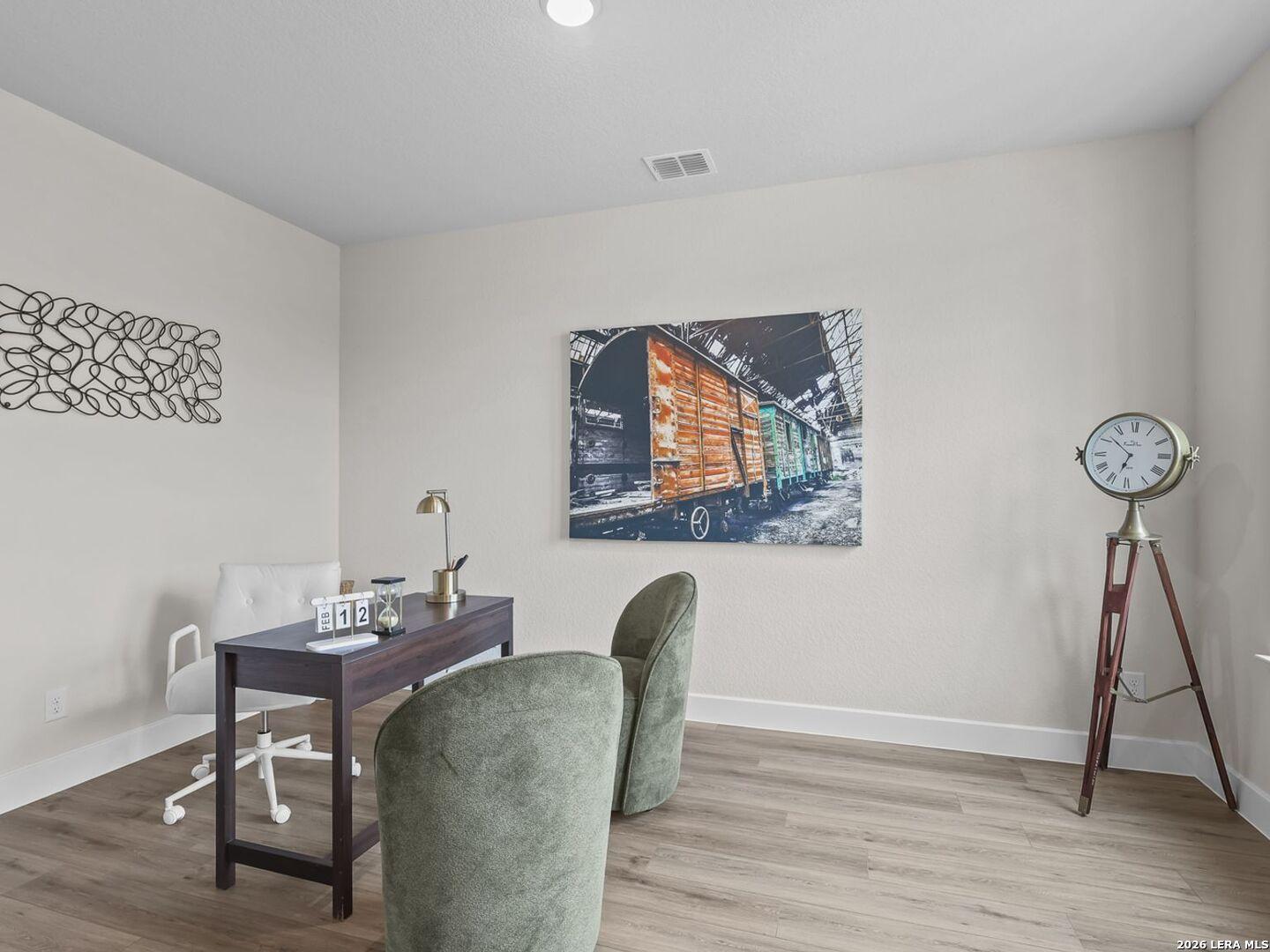 Modern home office with wood desk and green chairs in The Belmont H floor plan at Potranco Oaks, Castroville, Texas.